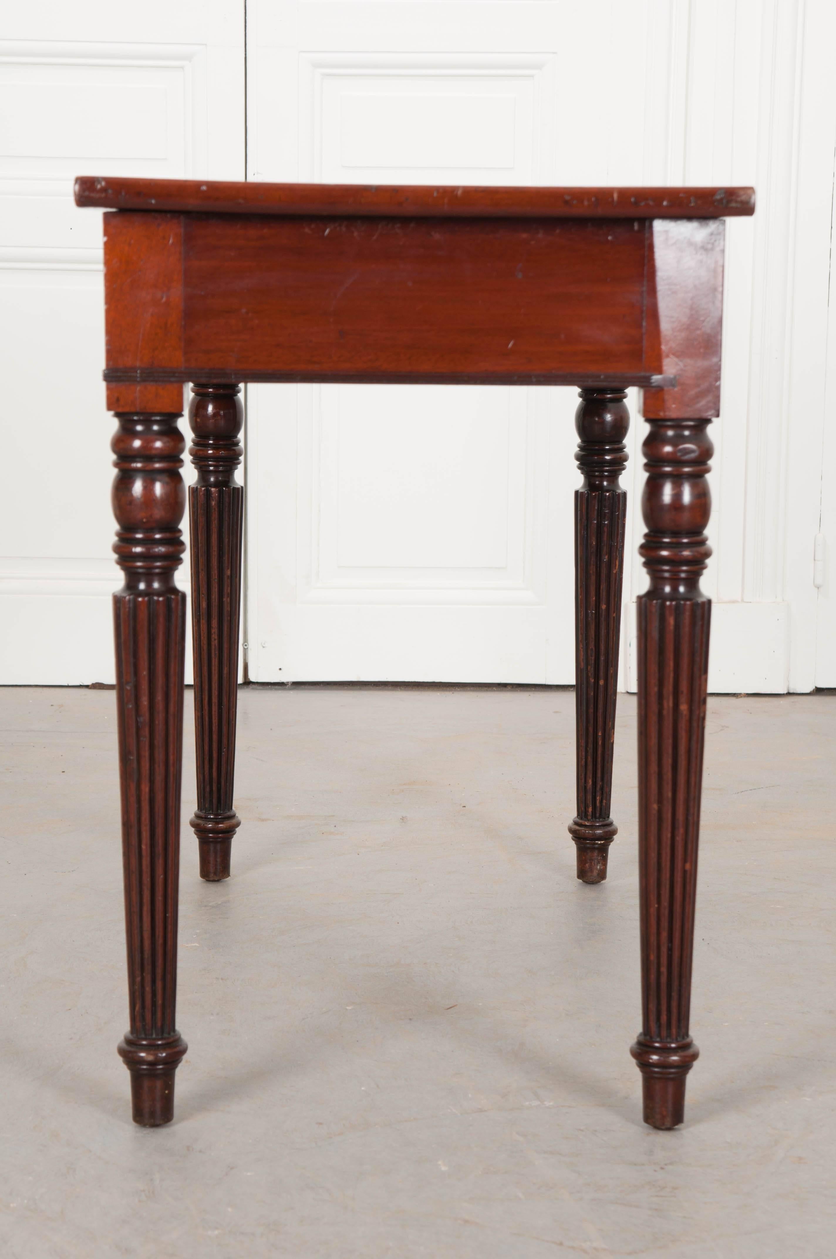 This handsome mahogany desk has been made in the Regency style in England, circa 1840. The top is covered in an outstanding olive-green leather, which has patinated wonderfully, and has been trimmed in marvelous gold tooling. The desk has two