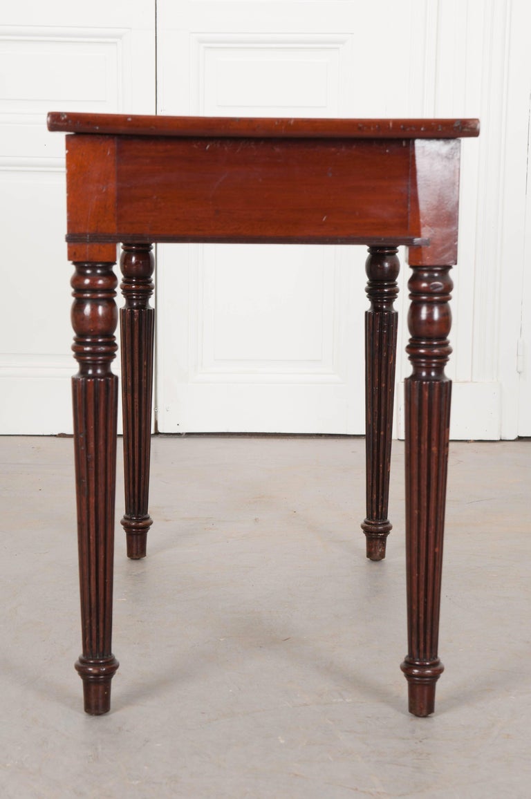 This handsome mahogany desk has been made in the Regency style in England, circa 1840. The top is covered in an outstanding olive-green leather, which has patinated wonderfully, and has been trimmed in marvelous gold tooling. The desk has two
