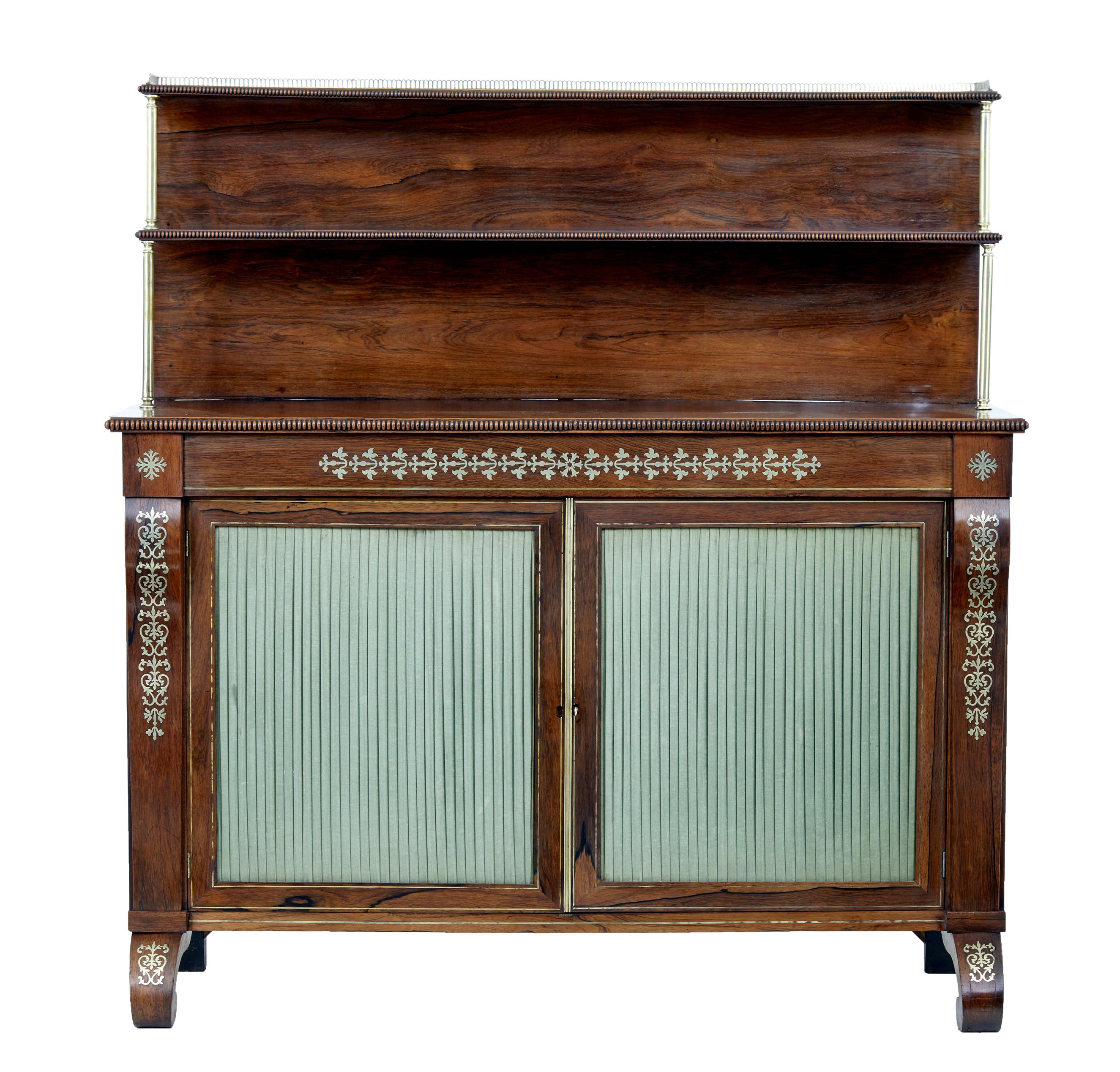 Fine quality Regency period chiffonier, circa 1820.

Top shelf with brass gallery detailed with a beaded edge. Second shelf supported by brass column supports. Main body beautifully decorated with inlaid brass designs to the front and legs. Double