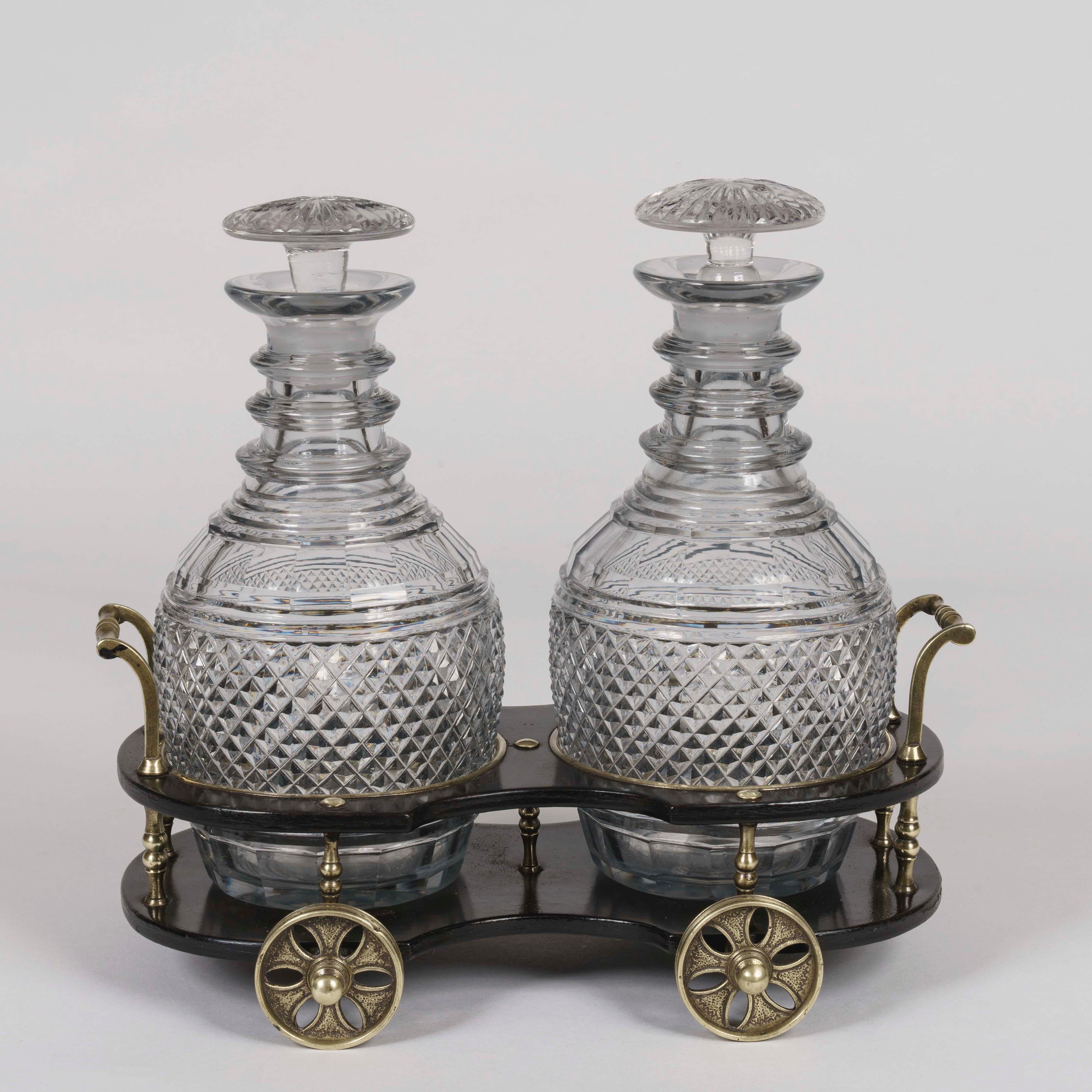 A Regency papier mâché and brass-mounted
Decanter Wagon

Constructed from dark painted papier mâché, the coaster trolley having four wheels and a brass balustrade alongside the twin-carrying handles; fitted with two cut-glass decanters and