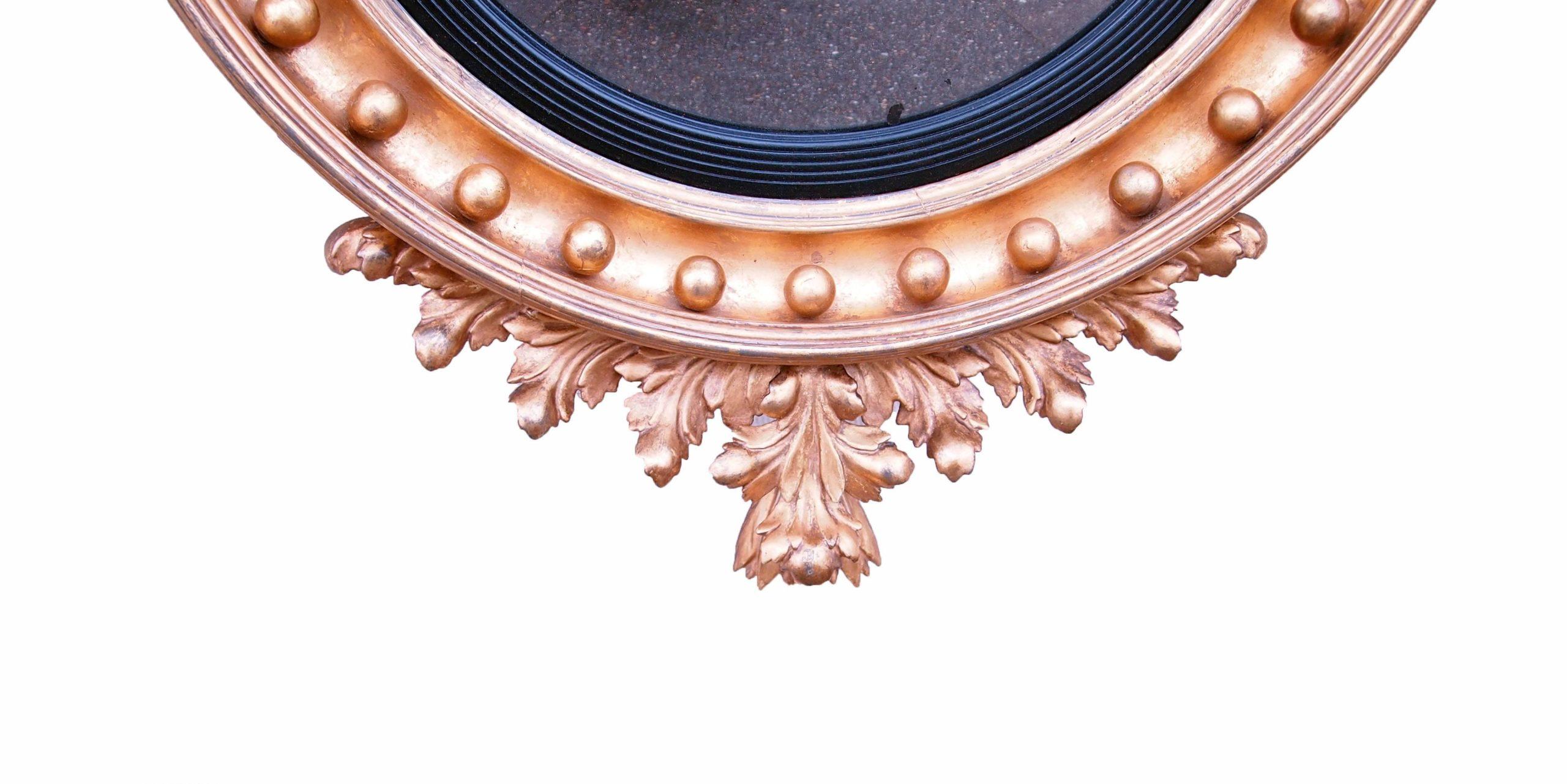 19th Century (Regency Period, 1820s) English giltwood convex mirror with unusual bold carved eagle surmounted to top and foliate carved decoration on bottom.
 