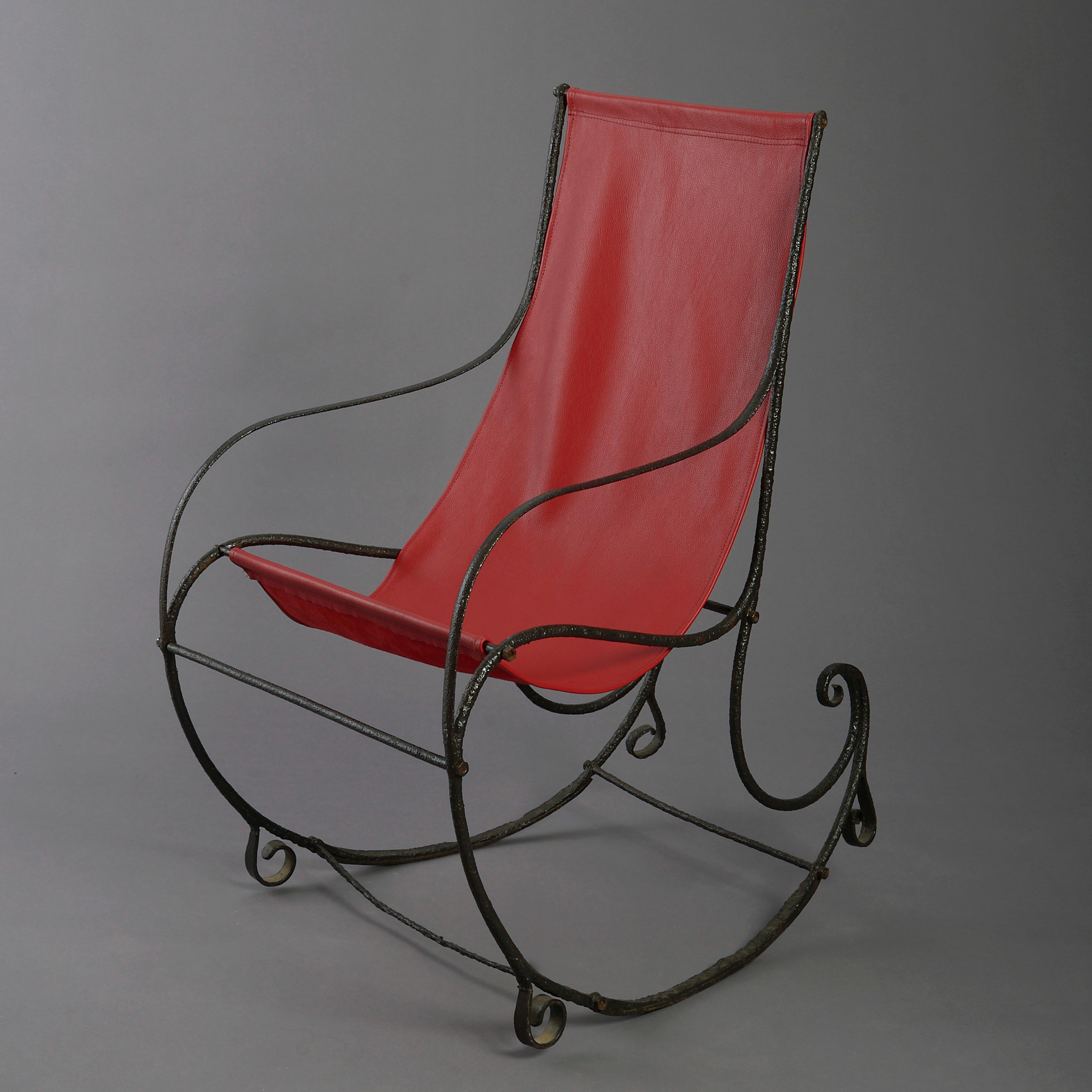 A Regency period cast iron rocking chair, having a rectangular back, with wrought iron scrolls to the arms and base. With red leather seat.