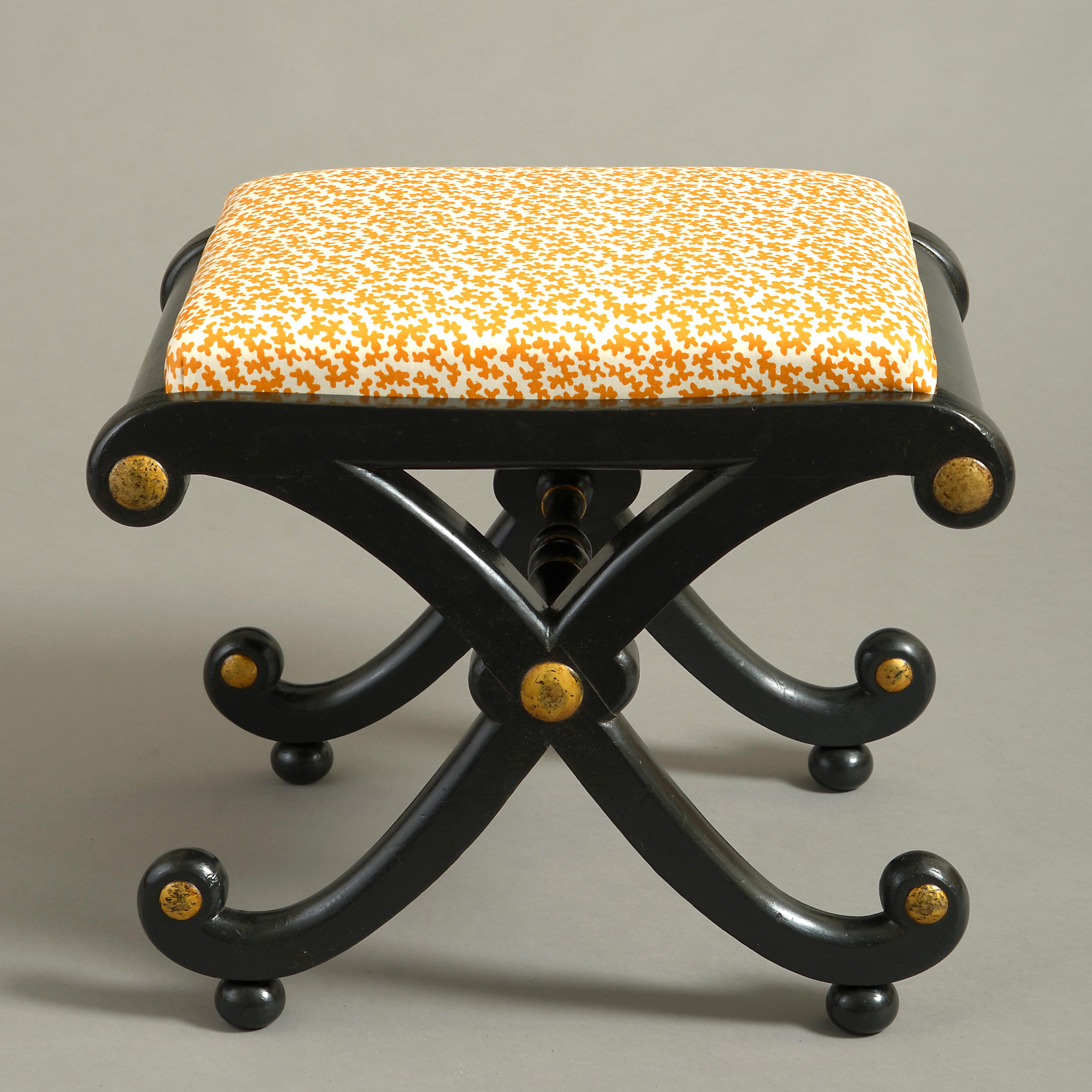 An early 19th century ebonized stool, the upholstered seat set into a rectangular frame with scrolling X-form legs, with gilded roundels and raised on ball feet.

The fabric: vintage colefax and fowler squiggle.