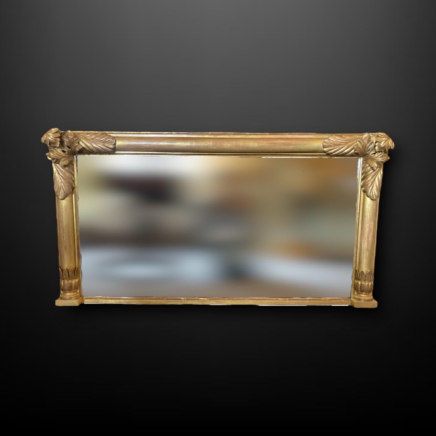 Miroir de style Régence du 19ème siècle en bois doré, bordé d'élégantes colonnes semi-tournées et d'un miroir en forme de manteau.  Décoration de feuilles sculptées.