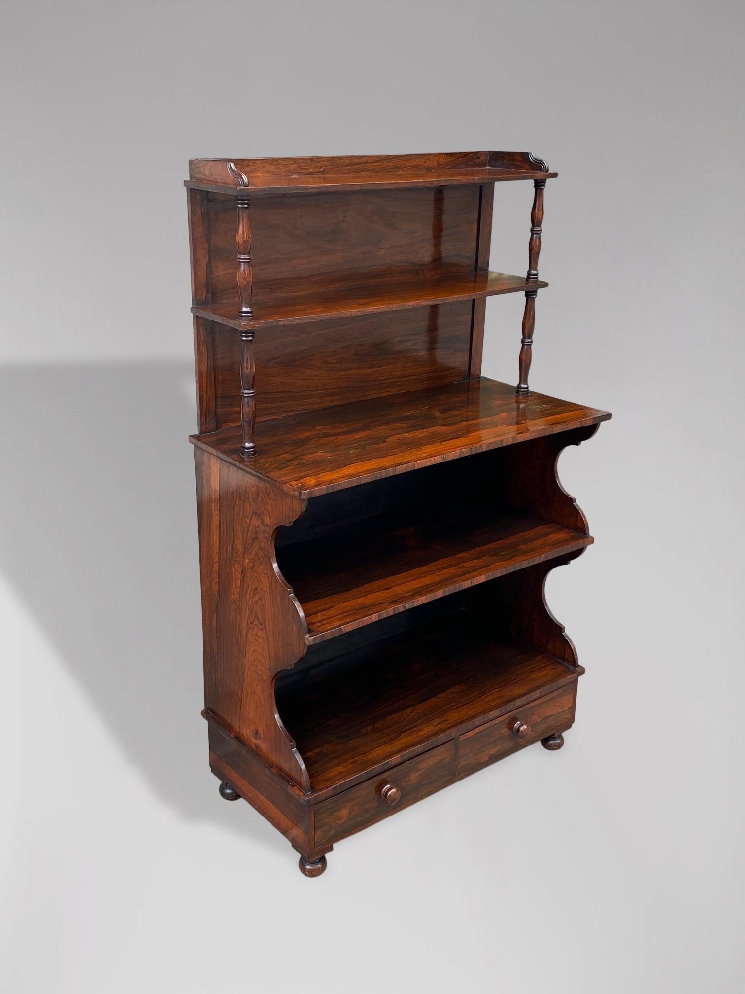 An unusual and very fine early 19th century rosewood waterfall open bookcase. A three quarter gallery superstructure with shelves above a shaped open bookcase with a pair of drawers, all standing on 4 bun feet with beautiful small brass castors.