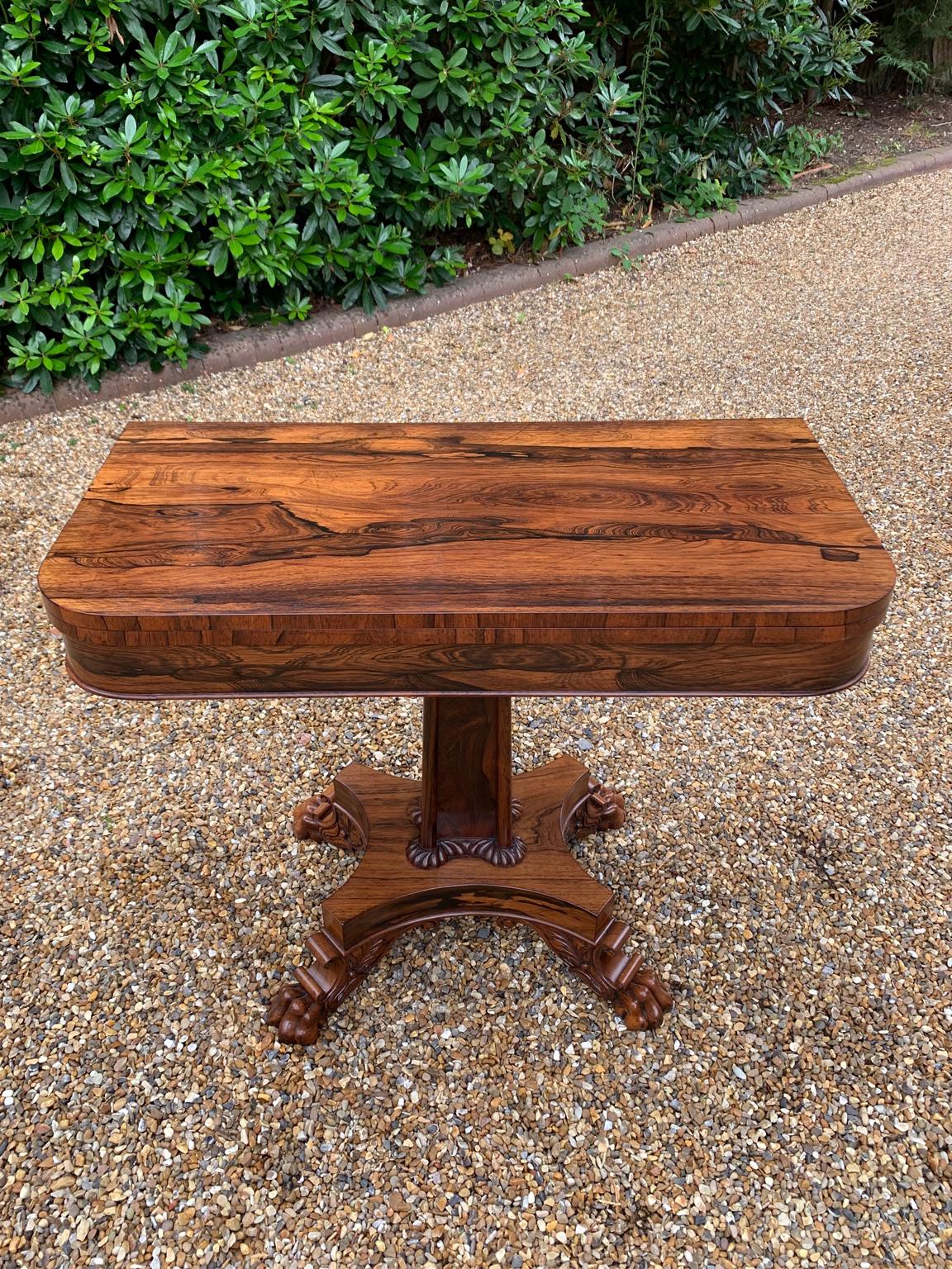A beautiful 19th Century figured Regency Rosewood Tea Table. The top rotates by 90 degrees and unfolds to convert to a Tea Table. The table stands on an elegant solid rosewood turned carved column on a quatrefoil base with four carved lion claw feet