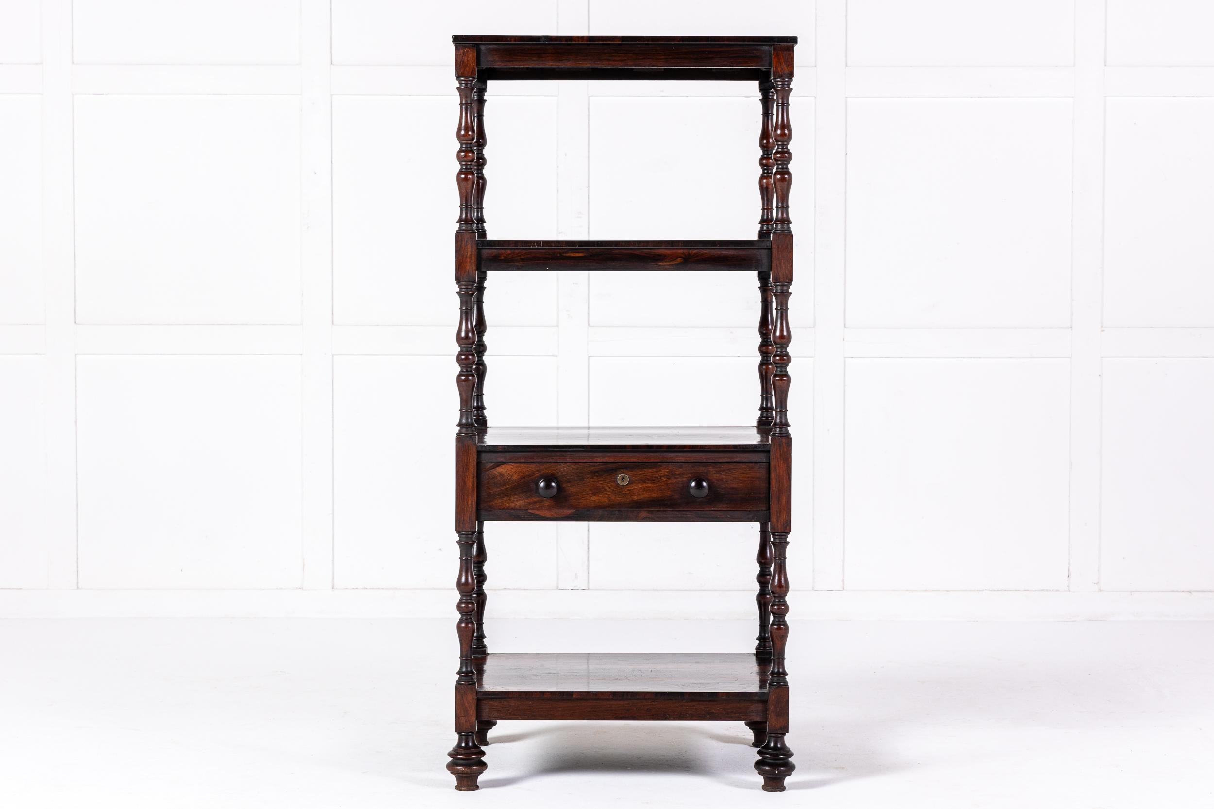 An Excellent Quality English Regency Period Rosewood Whatnot.

Consisting of four rosewood veneered shelves, one with a slim drawer, connected by four decorative turned columns and supported on unusually shaped turned feet.

What sets our piece