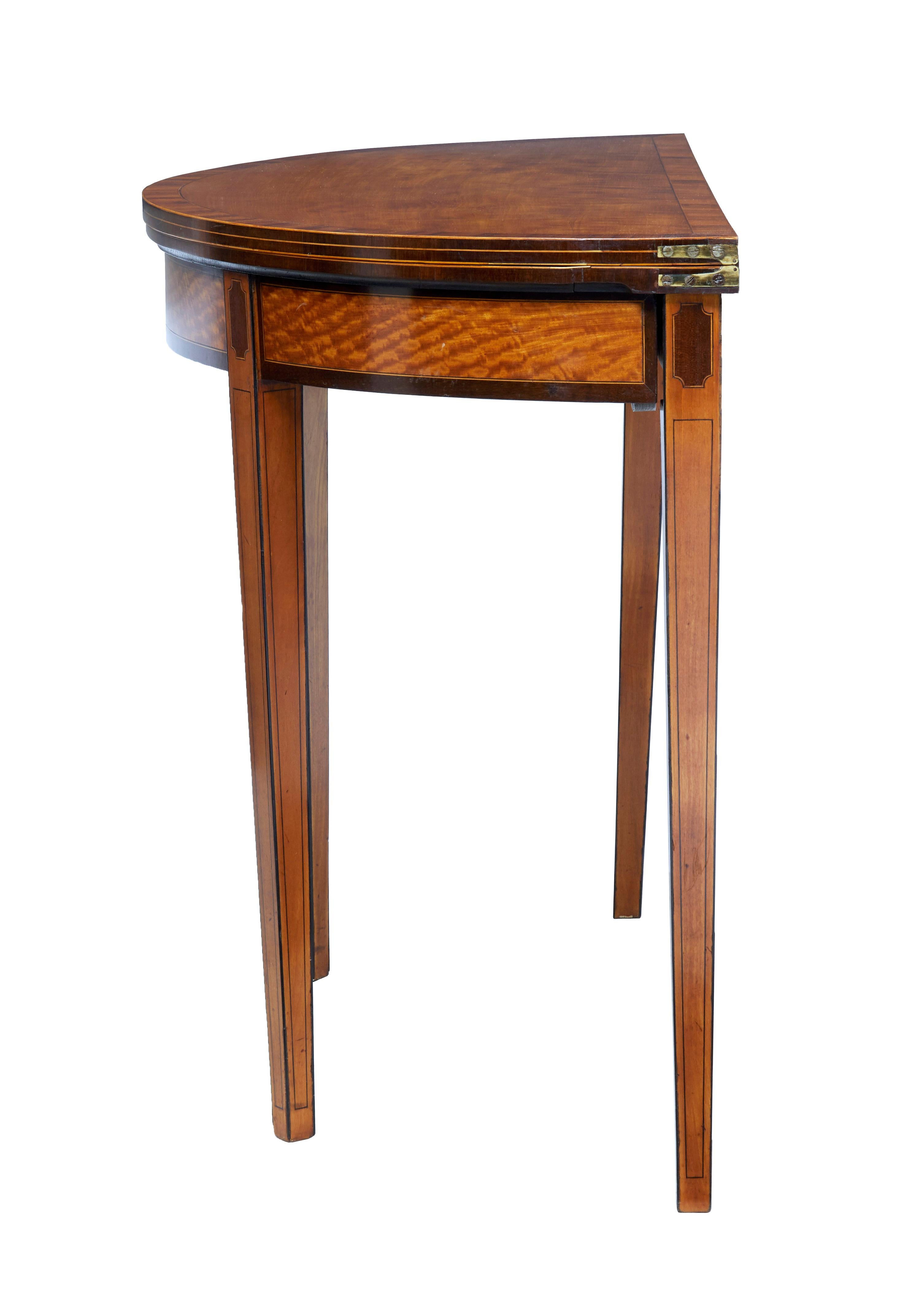 Fine quality demilune Regency card table, circa 1820 with strong Sheraton influence.

Top surface cross banded and box wood strung, opening out to a later green baize playing surface. The frieze has been fiddle back cut which allows a delightful