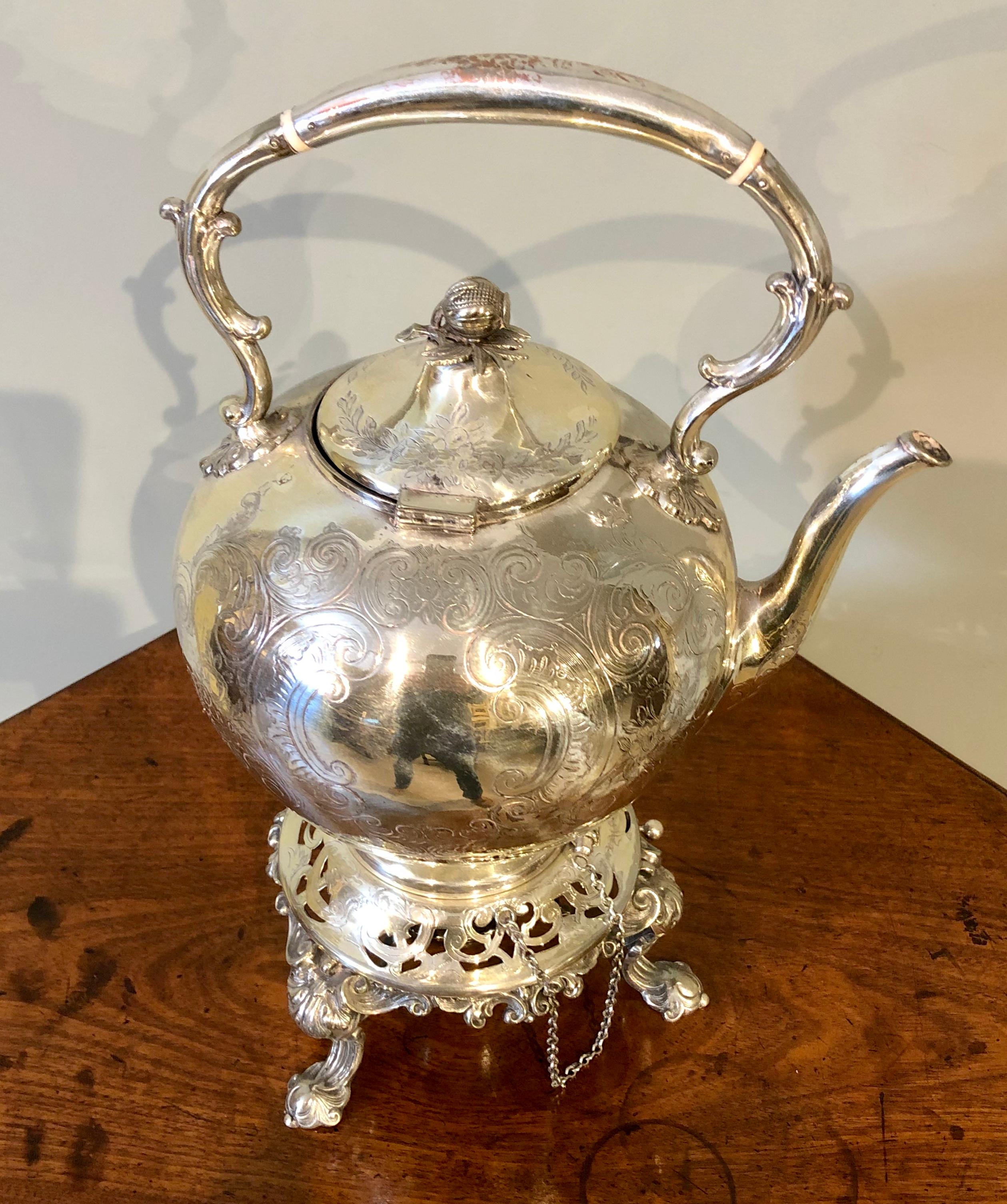 A wonderfully decorative 19th century Regency style silver plate tilting teapot with burner. Floral scroll engravings decorate the teapot surrounding the uninscribed cartouches.