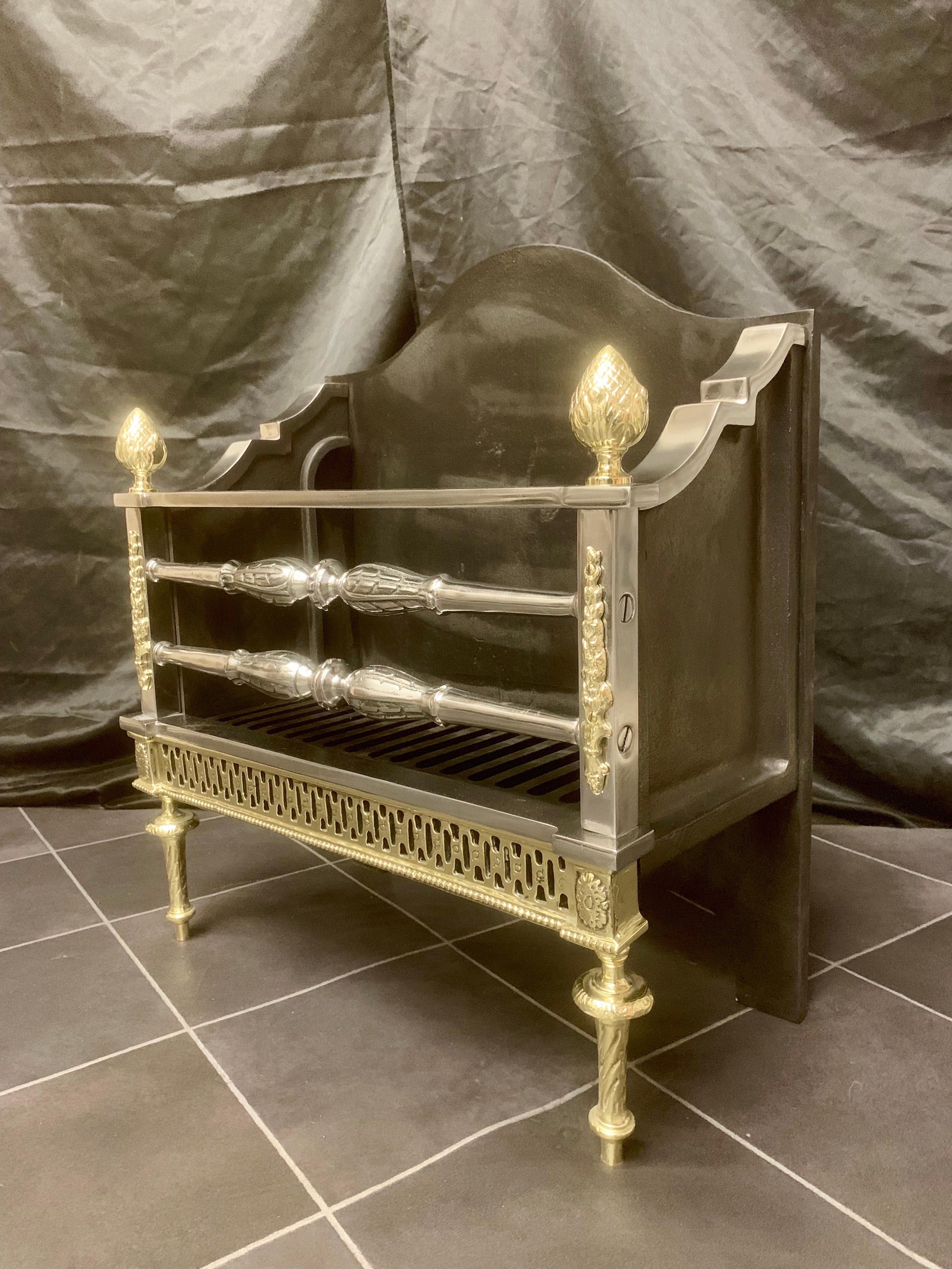 A neat Regency 19th century style brass and polished steel fire grate basket, a high shaped back plate with polished sides holds a three barred fire front flanked by polished steel posts with applied brass drops mounted with Bud acorn finials. a