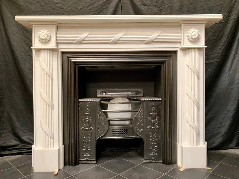 A medium sized 19th century Regency style hand carved statuary marble fireplace surround, a reeded top shelf sits directly above a stepped frieze with carved ribbon and reeding, flanked by framed high relief circular pateraes to the end blocks,
