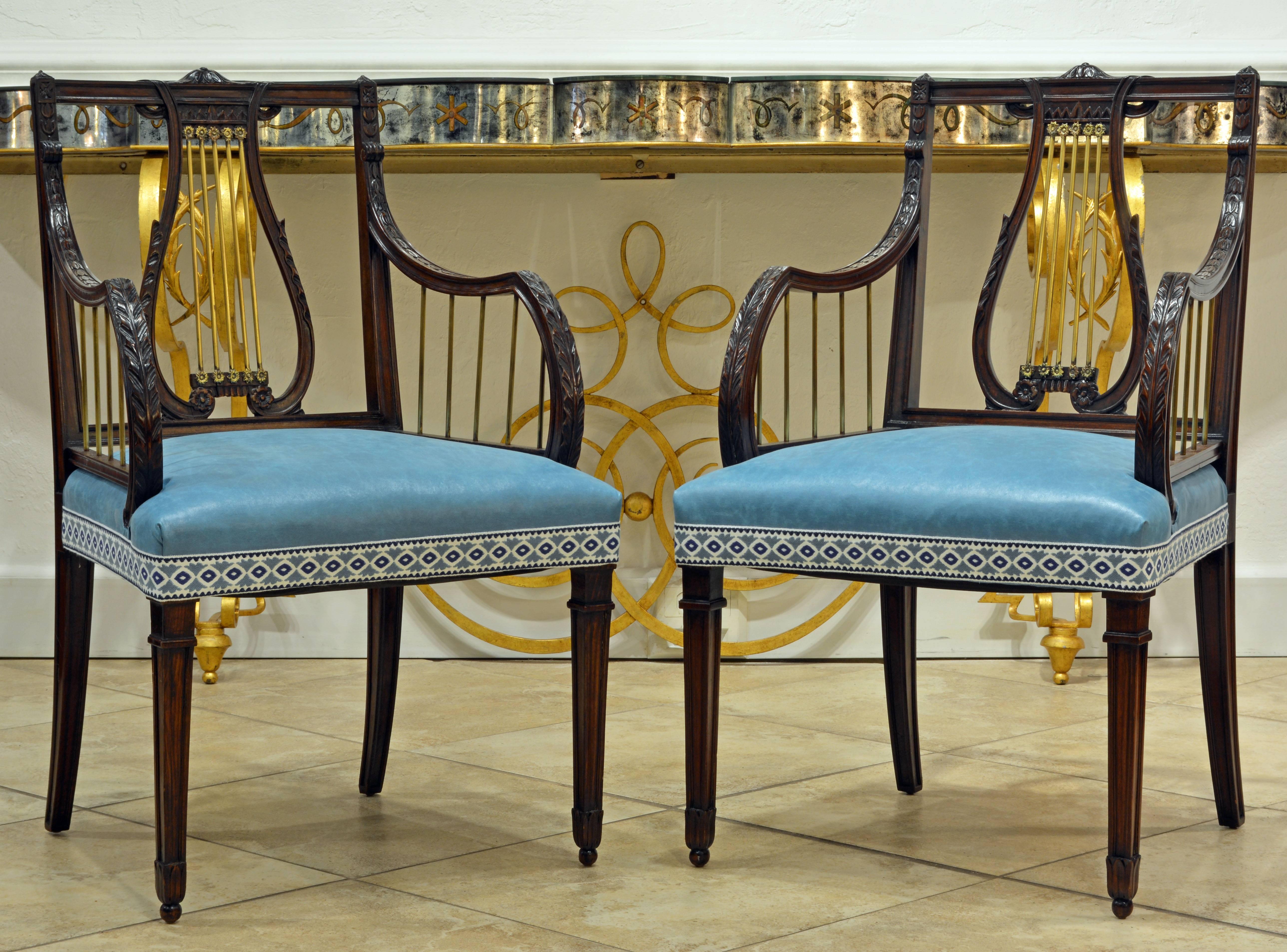 Dating to the late 19th century this elegant pair of Regency style armchairs features a carved mahogany frame with bronze accents in the lyre style on back and armrests. They are attractively covered with pristine light blue chintz and trim.