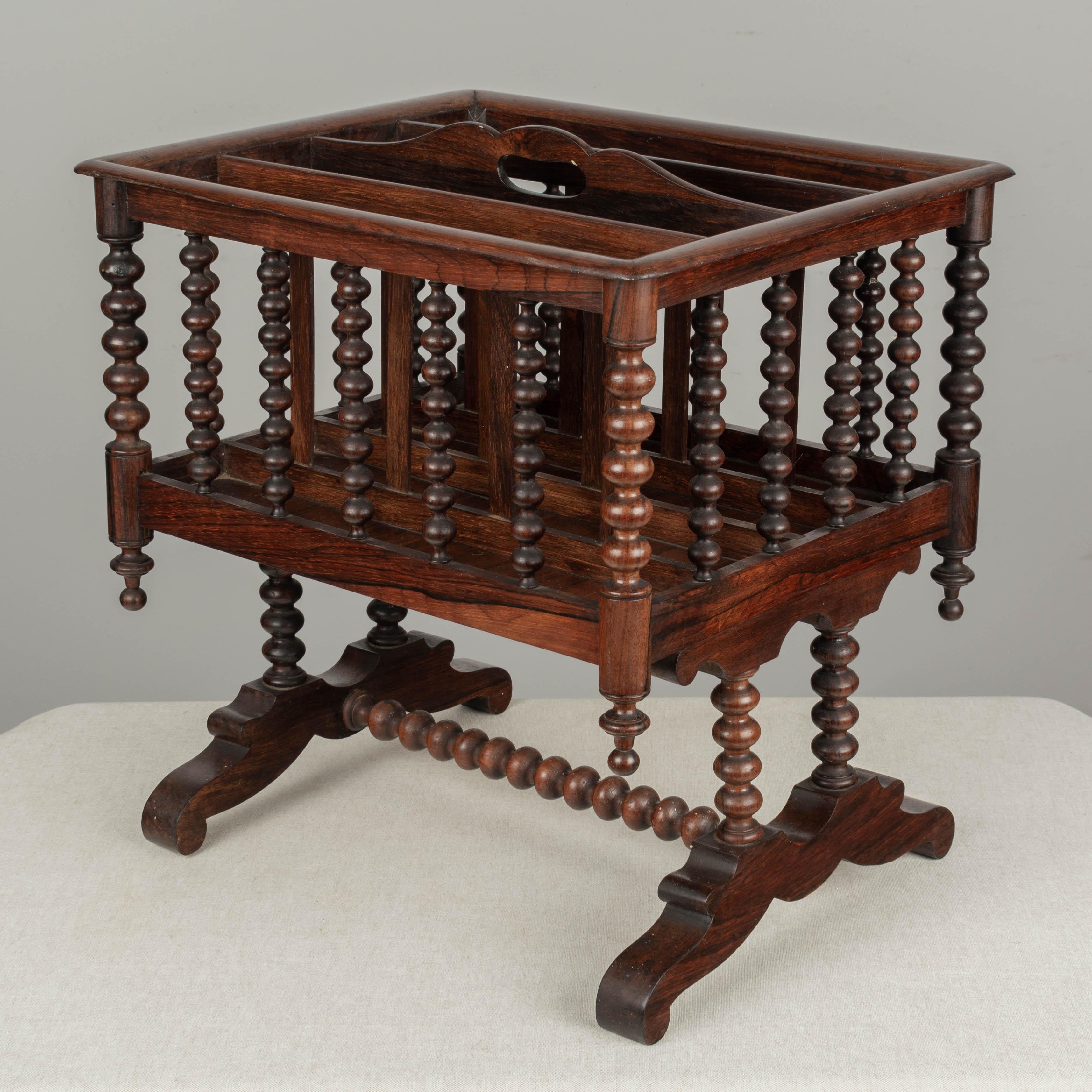 A fine 19th century English Regency style rosewood four-section canterbury for sheet music, or magazine rack. Highly decorative turned spindle frame with carrying handle, raised on legs with spindle stretcher.