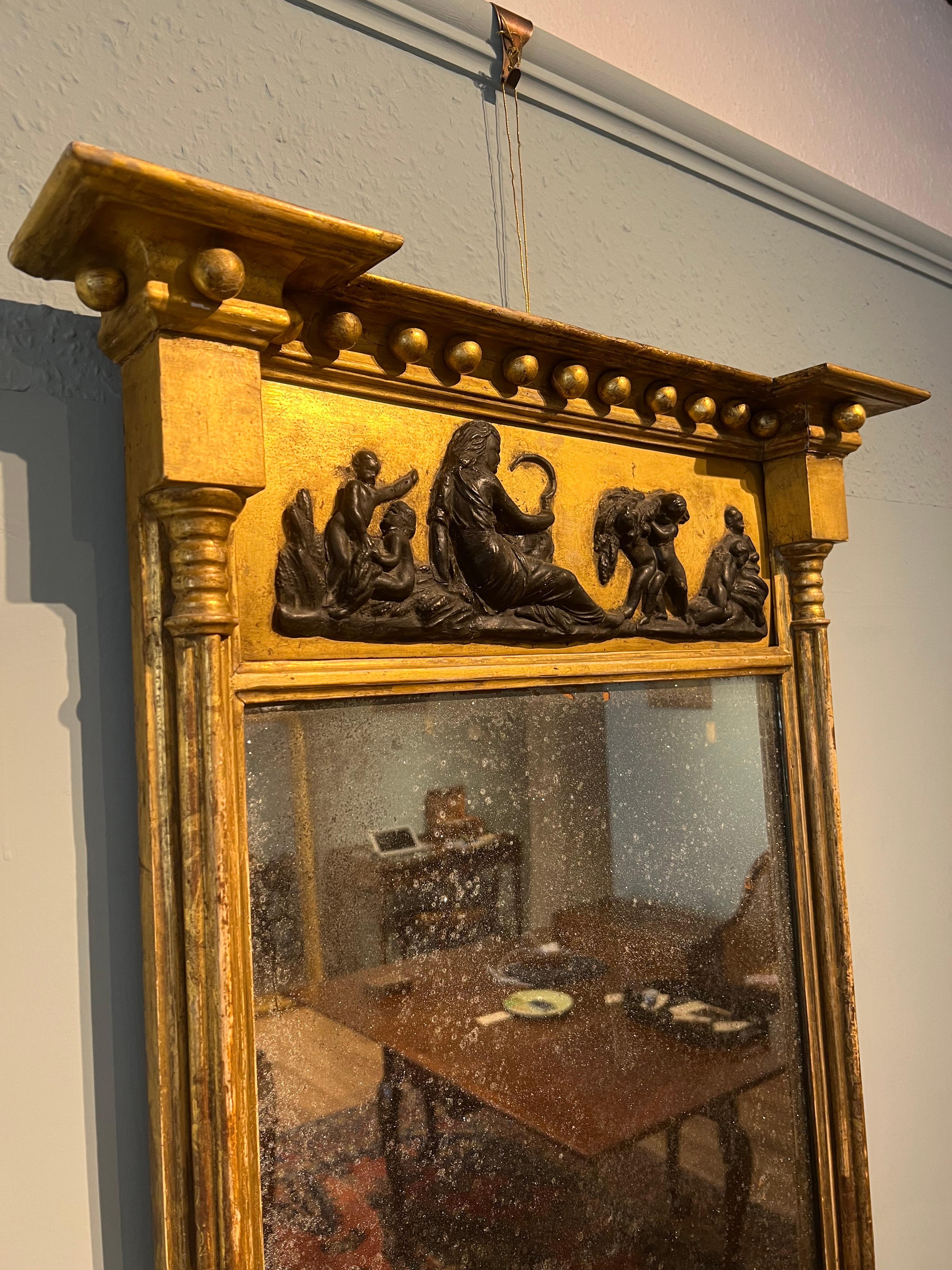 Fine Regency period gilt pier mirror, in untouched original condition. This lovely rectangular pier mirror has ball decoration to the cornice, below this there is an ebonized Greek harvest scene. Cluster column pillars are to the sides, with the