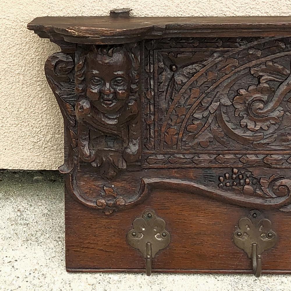 19th century Renaissance carved oak hat, coat rack is a splendid example of the sculptor's art! Hewn from dense, old-growth oak, it features three cherub's faces in full relief forming a framework for the lavishly carved panels depicting foliates,