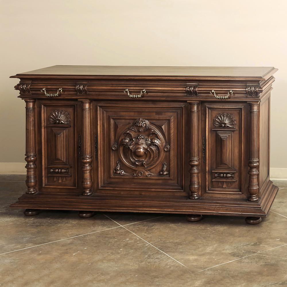 Beautifully carved from solid French walnut with naturalistic forms in bold relief balanced by stylized shells and architectural motifs, this handsome Antique French Renaissance Henri II style Buffet boasts bold molding and four columns to create