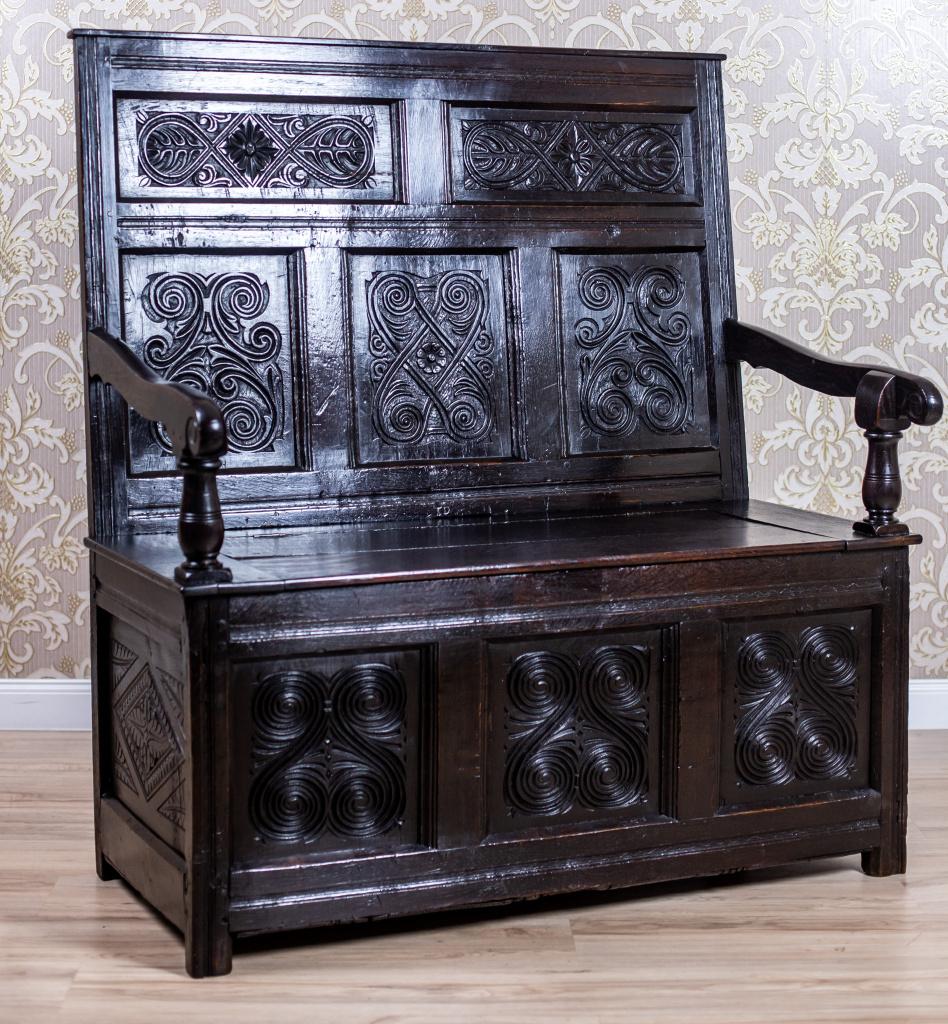 19th-Century Renaissance Revival Oak Bench in Dark Brown

A two-seater bench in the Renaissance Revival style made of solid oak wood. The piece resembles a chest with a lift-up seat and a simple high backrest, adorned with volute-shaped armrests.