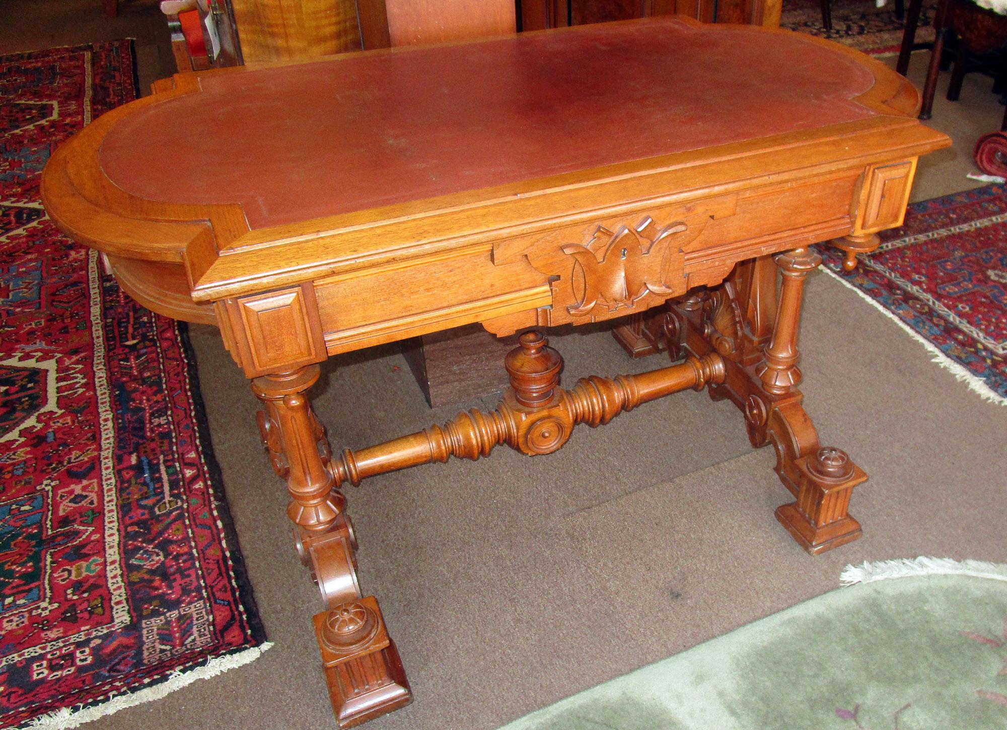 Very ornately carved Renaissance Revival rich golden oak desk or library table with leather insert, that we believe to be original. Features include a sectioned front drawer with large carved key frame, double fluted tapered columns on either side