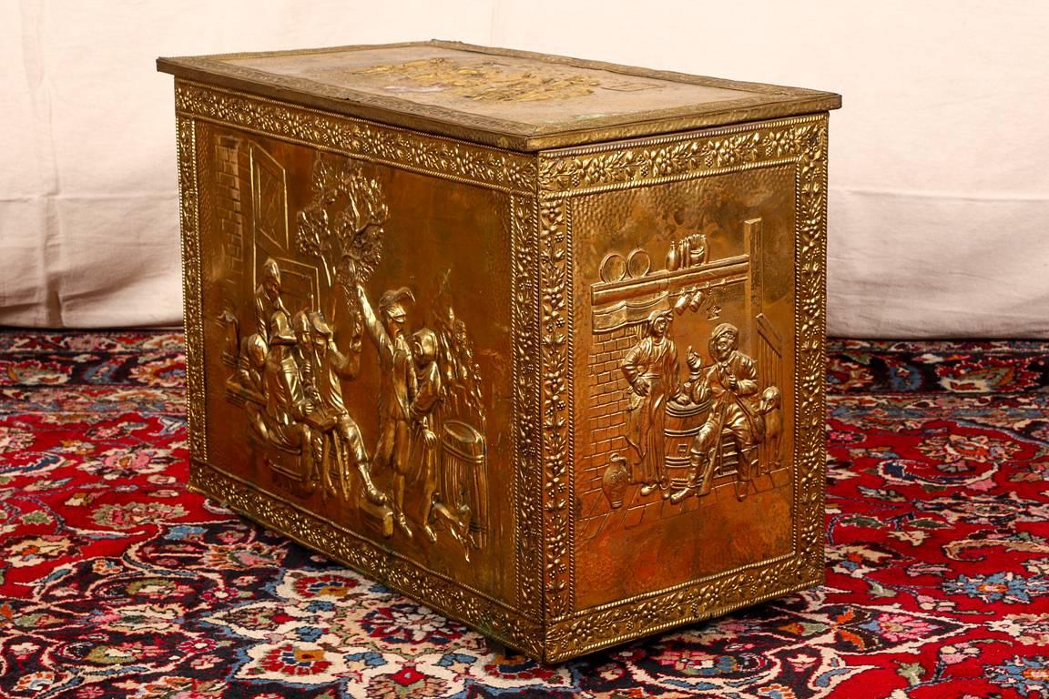 19th century repousse brass tinder box, the repousse hinged lid with figures at a tavern, and the outside panel with an outdoor tavern scene with figures at a table, a barrel and a dog. The side panels with figures and a barrel. With floral