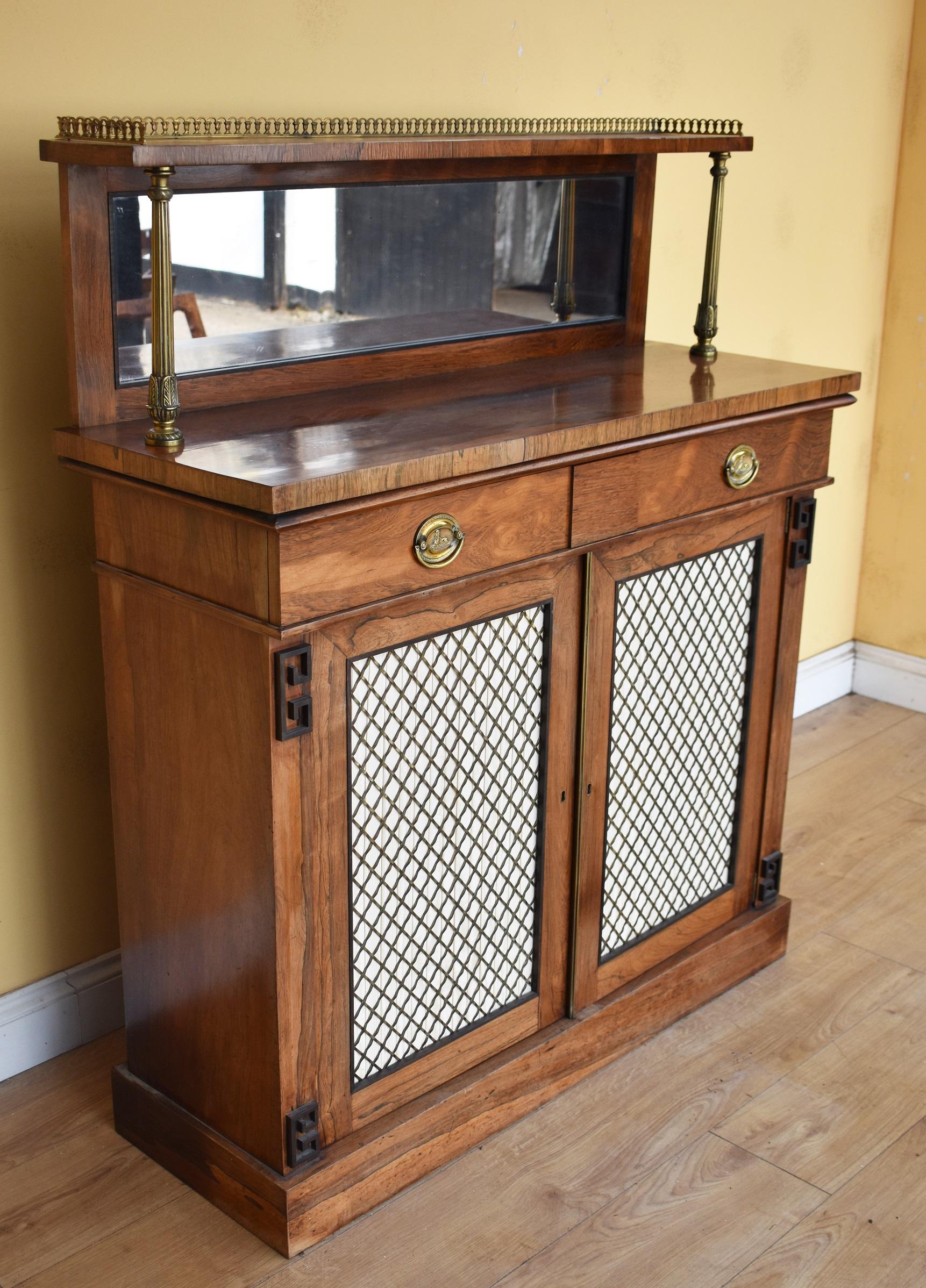For sale is a good quality Regency rosewood chiffonier with brass gallery shelf, above a drawer with two brass handles above two cupboard doors, each with brass grille and silk lining, opening to reveal a single shelf. The chiffonier is raised on a