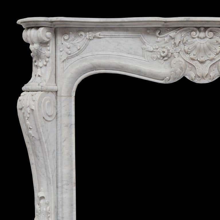 A rich and beautiful 19th century antique French sculpted Louis XVI white Carrara marble fireplace mantel. Hand carved with a serpentine shelf with, detailed frieze which is powerfully carved together with a foliated shell, flowers and panels. The