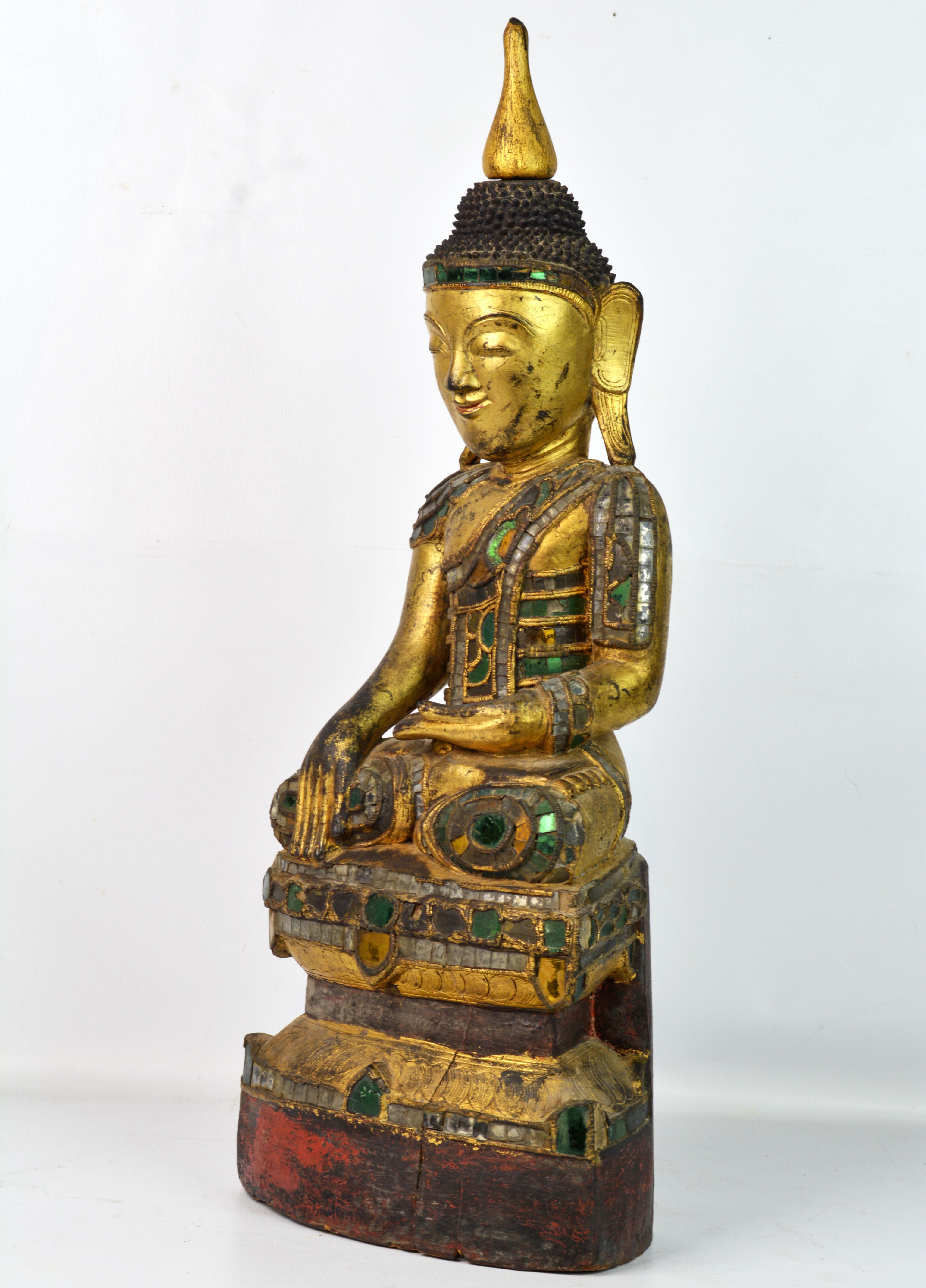 Rare late 19th century Burmese carved, lacquered and gilt Buddha with rich polychrome glass inlay. The historical Buddha, Shakyamuni, is portrayed in bhumisparsha mudra, the gesture of calling the Earth to witness, commemorating the moment the
