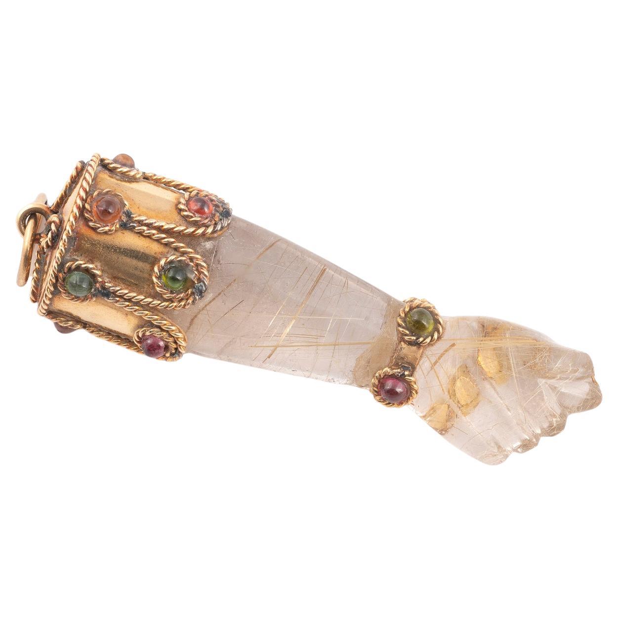 The rock crystal hand realistically modelled with the thumb between the first two fingers surmounted by a gold cap embellished with cabochon cut semi-precious stones, length 80mm including loop.
Weight: 33gr.
A higa jewel (sometimes known as a figa)