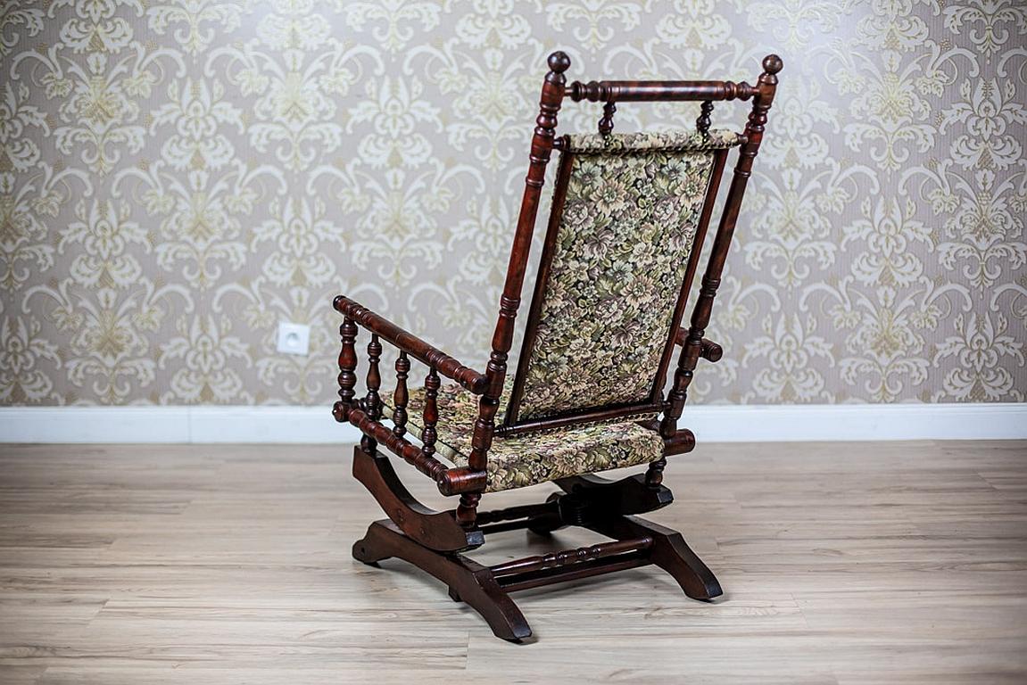 Fauteuil à bascule éclectique du 19e siècle en tissu floral

Chaise à bascule éclectique du 4e quart du 19e siècle. La chaise présente un cadre en bois avec des éléments en fuseau tourné formant un dossier et une assise, tapissés de tissu. La base a
