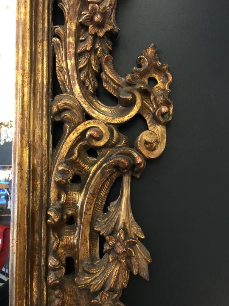 A magnificent 19th century Rococo style wall mirror with hand carved gold leaf gilt wooden ornate frame with leaf, flower, scrolls and basket details. It has a wonderful large crest on top and the original glass.