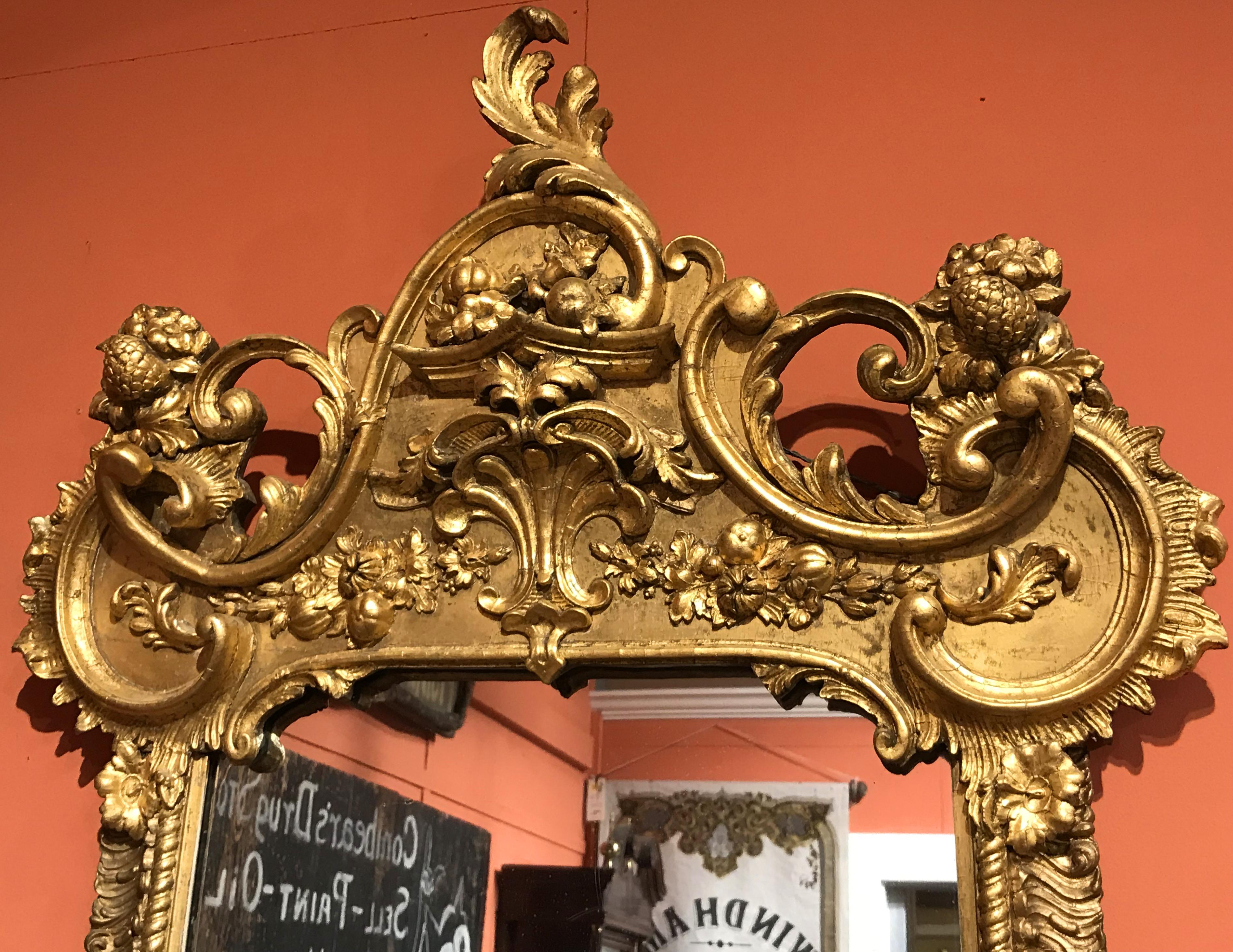 An exceptional Rococo giltwood pier mirror, with ornate pierce carved scroll and foliate crest surmounting a mirror flanked by rope twist and scrolled borders, terminating with corner dolphin and scroll decoration at the base. Probably Continental