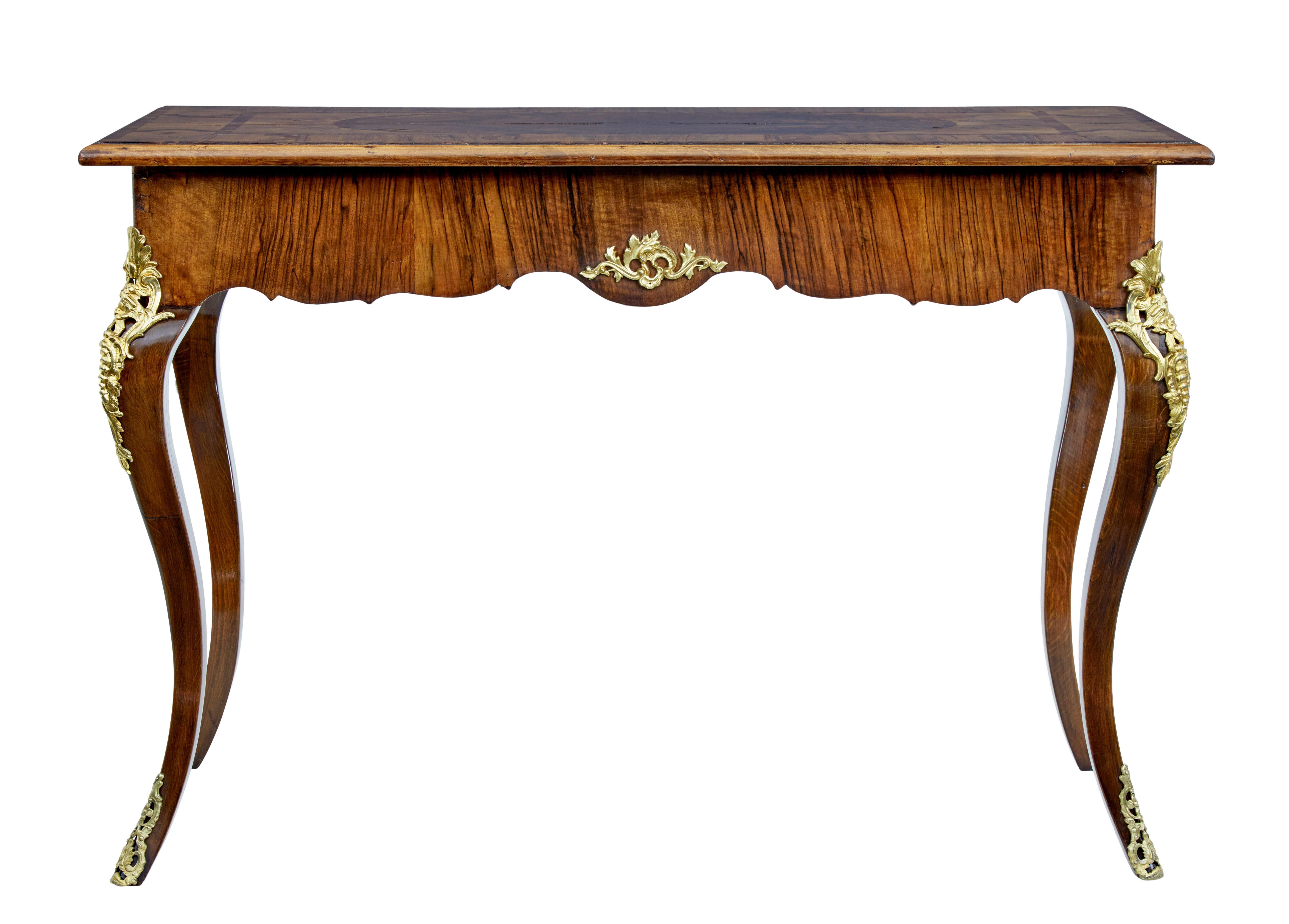 Beautiful walnut inlaid side table circa 1830.

Top surface with contrasting walnut veneers arranged into a symmetrical design. Shaped frieze with decorative ormolu mounts on each side. Further mounts on the top of cabriole leg and to the base of