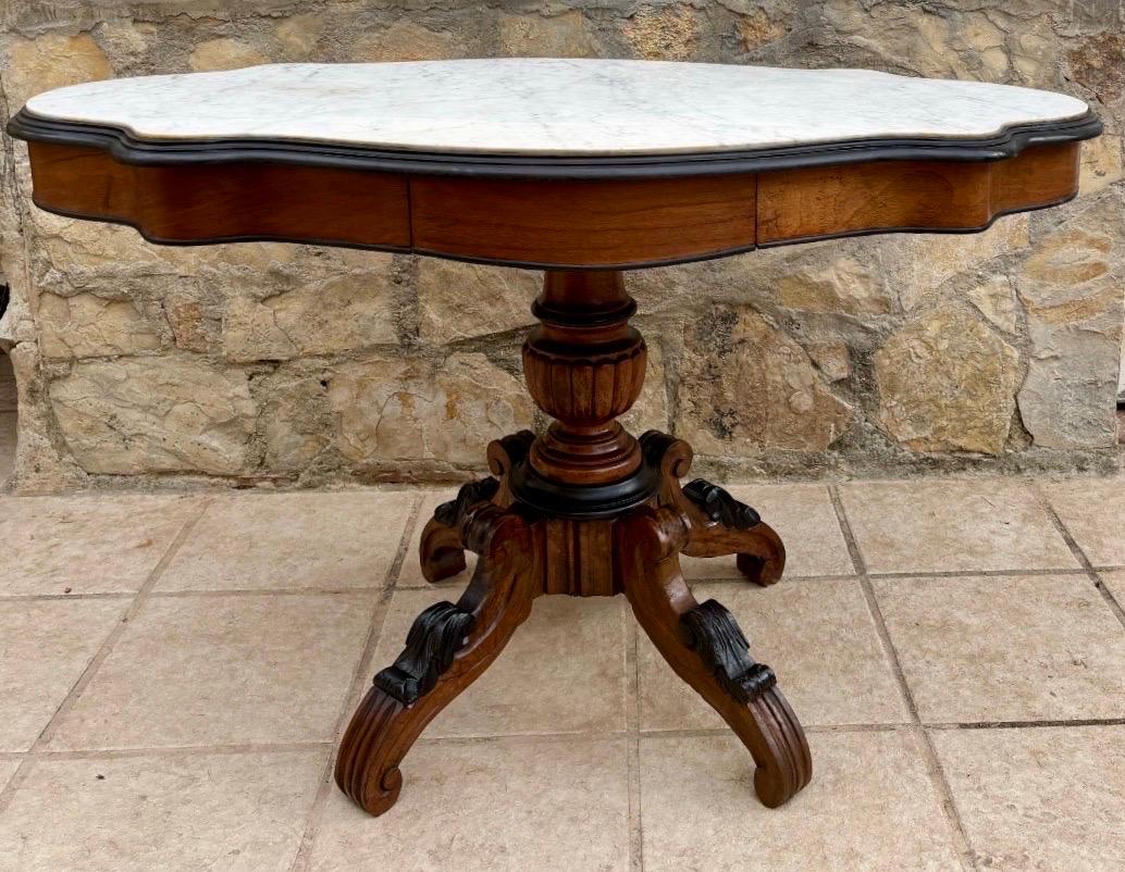 Elegante table centrale de la fin du 19e siècle, de style victorien néo-rococo, avec un plateau en marbre blanc magnifiquement façonné et une base en noyer massif richement sculptée. Le tablier en forme de serpentin abrite un petit tiroir incurvé,