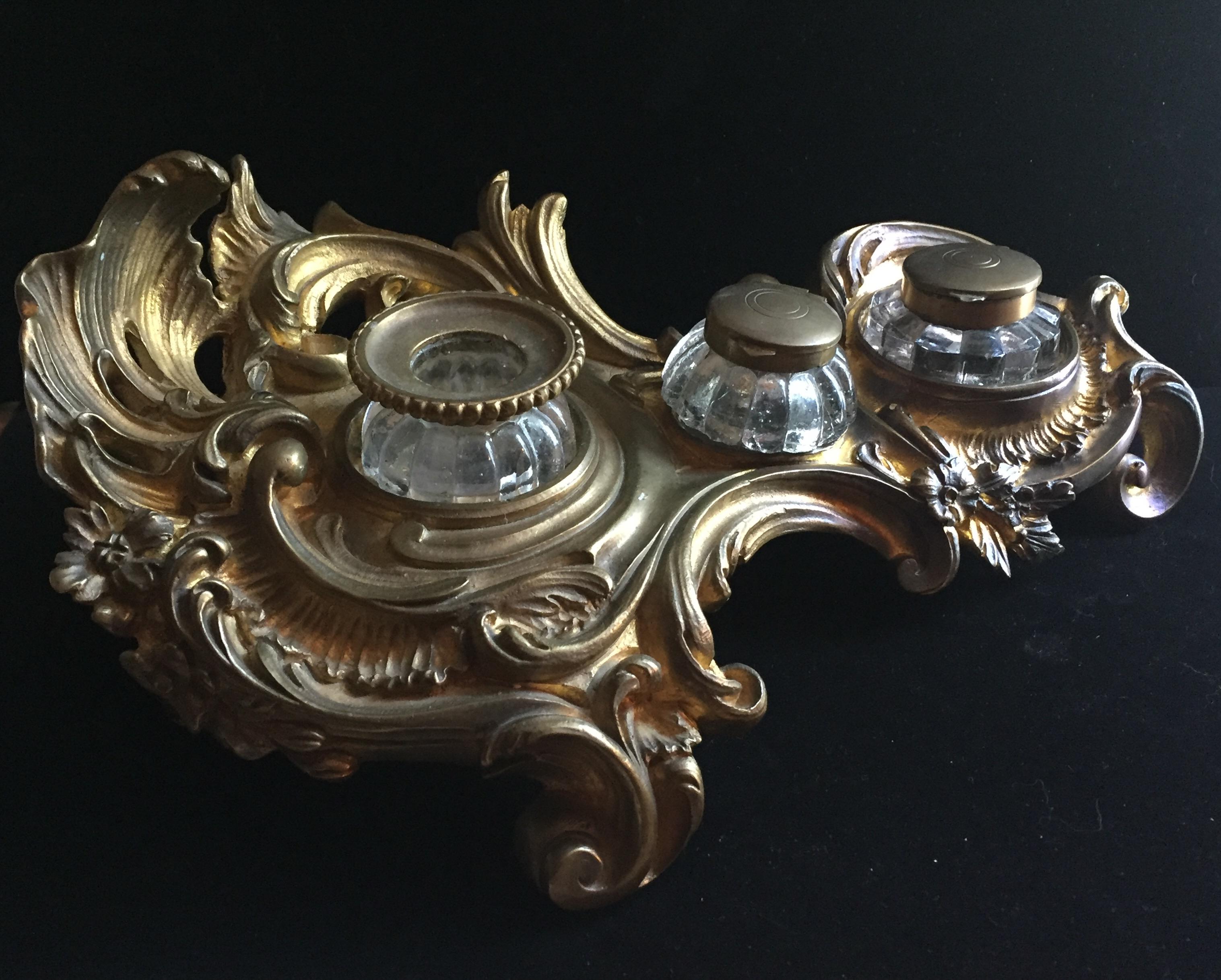 This fine 19th century encrier or inkwell is cast in Rococo revival with swirling weaves, scrolls and acanthus leaves. It is resting on an openwork base. The modeling is very fine with a reserve of two glass wells for ink and a glass candle