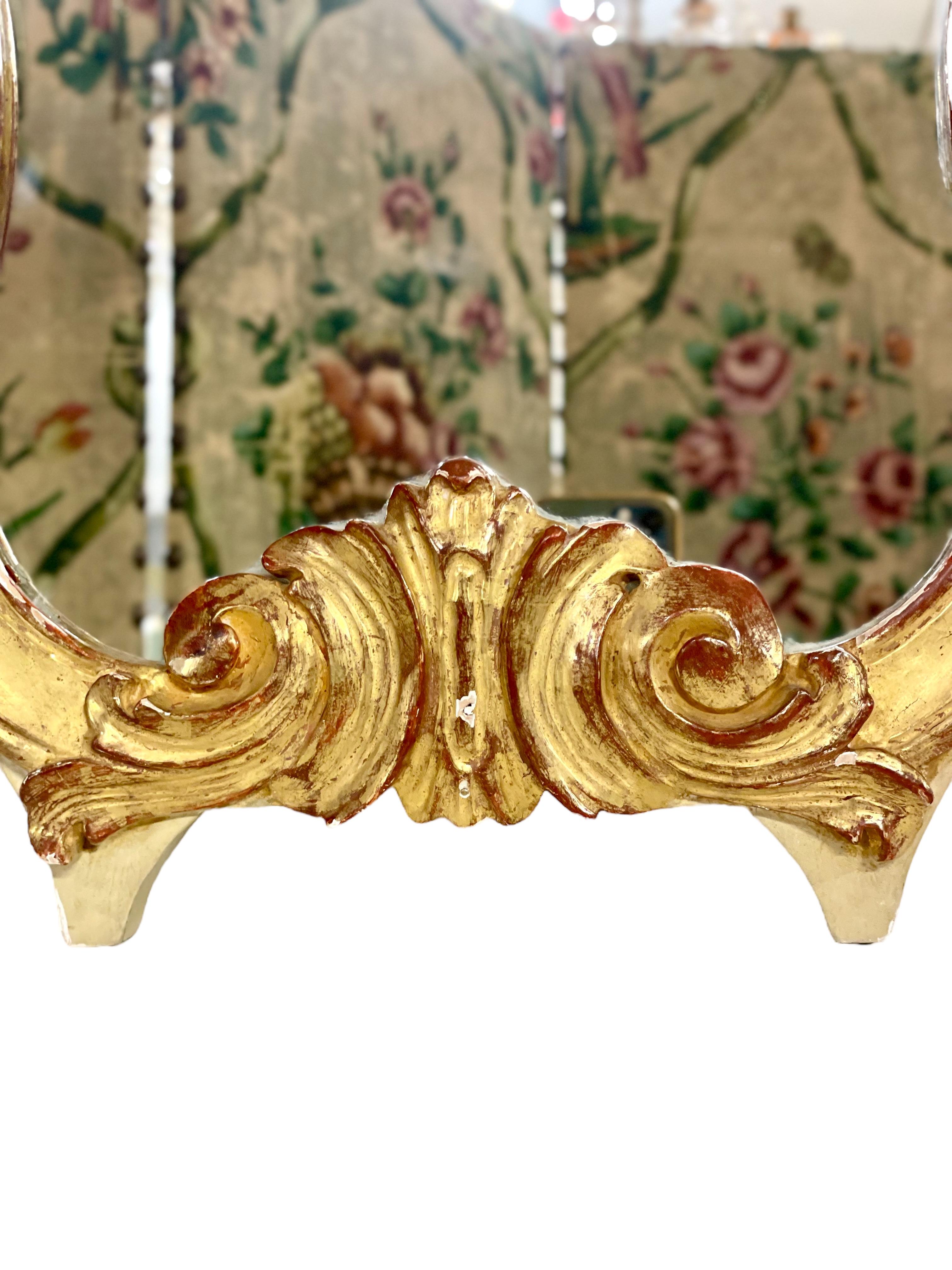 An exquisite violin-shaped Rococo-style wall mirror in hand-carved and gilded wood, with a beautiful stylised shell at its crest and swirling acanthus scrolls cascading down each shoulder, and at its base. Echoing the exuberant styling of the 18th