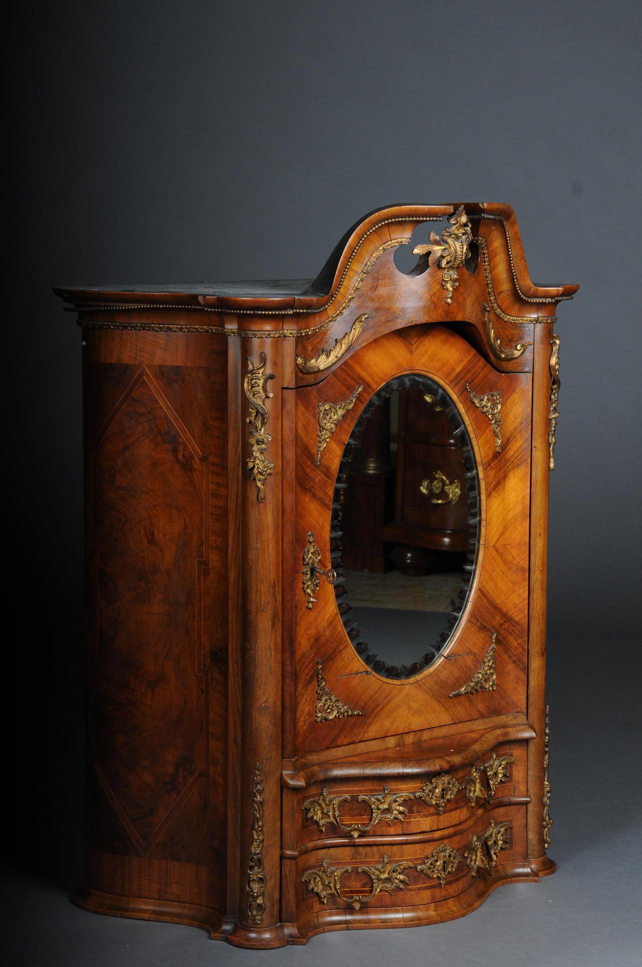 19th century Rococo top cabinet walnut root, Germany 
Walnut root veneer on solid wood. Top cabinet with 2-drawer fronts above a door with medallion shaped mirror, faceted. Gold-plated fittings

(O-252).