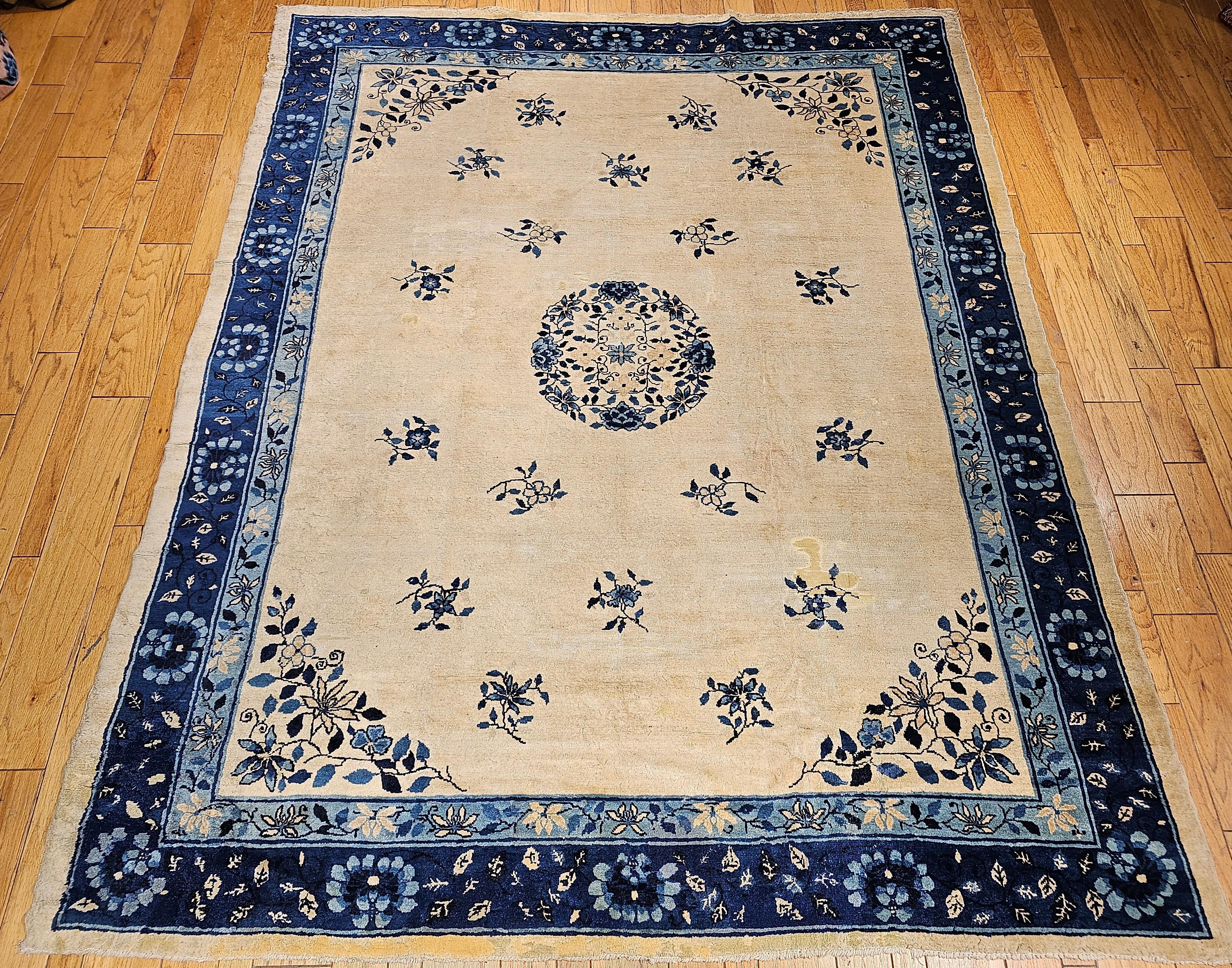 Vintage room size Chinese Peking rug from the late 19th century.  The rug has a beautiful natural or ivory color background containing the traditional Chinese flower bouquets and a wonderful central medallion in floral pattern framed by two shades