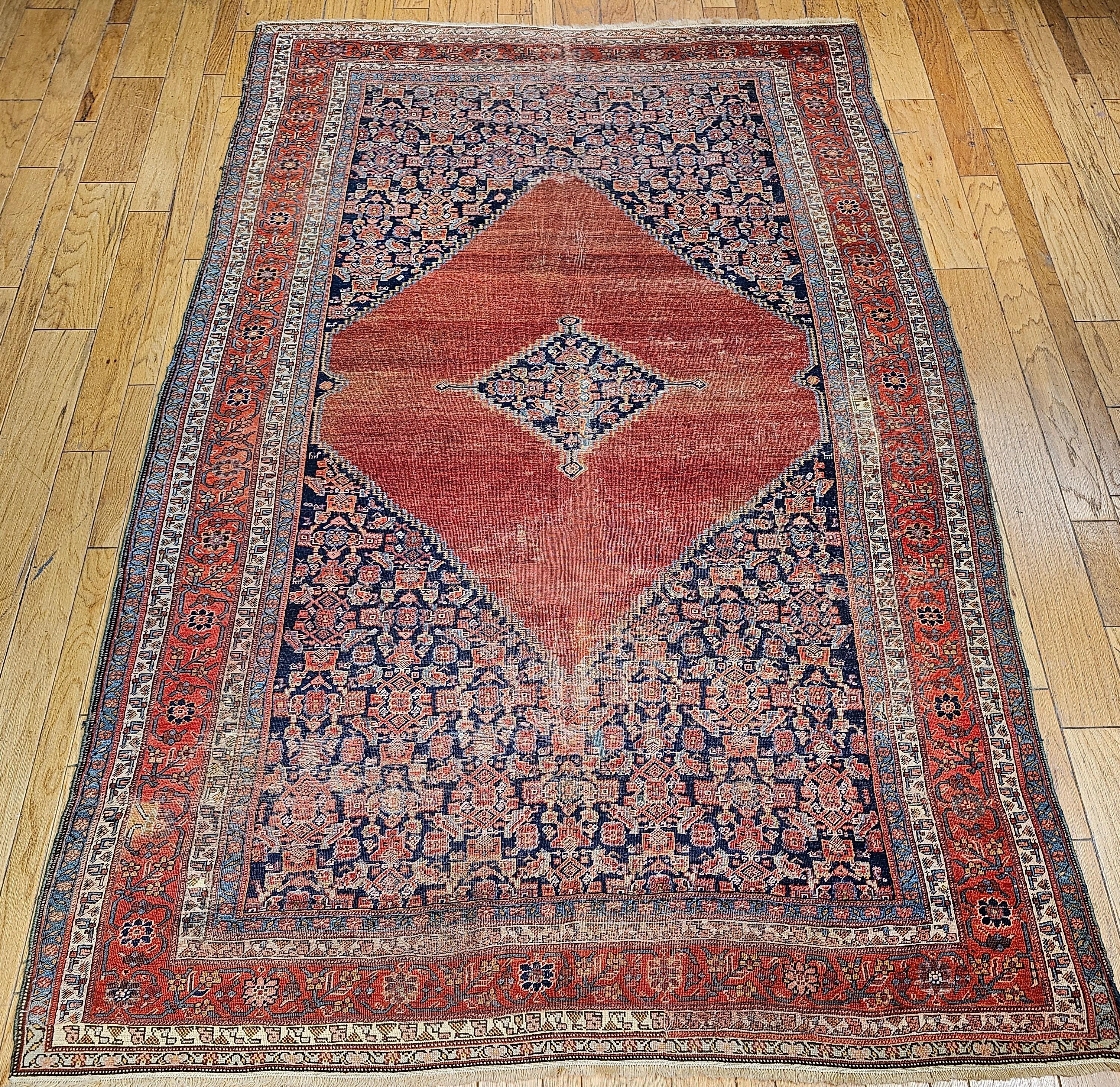 Astonishing beautiful antique Persian Malayer room size rug from the late 1800s. The rug has one of the most gorgeous medallion designs in terracotta red with a smaller central medallion in a dark navy blue color field which makes the combination
