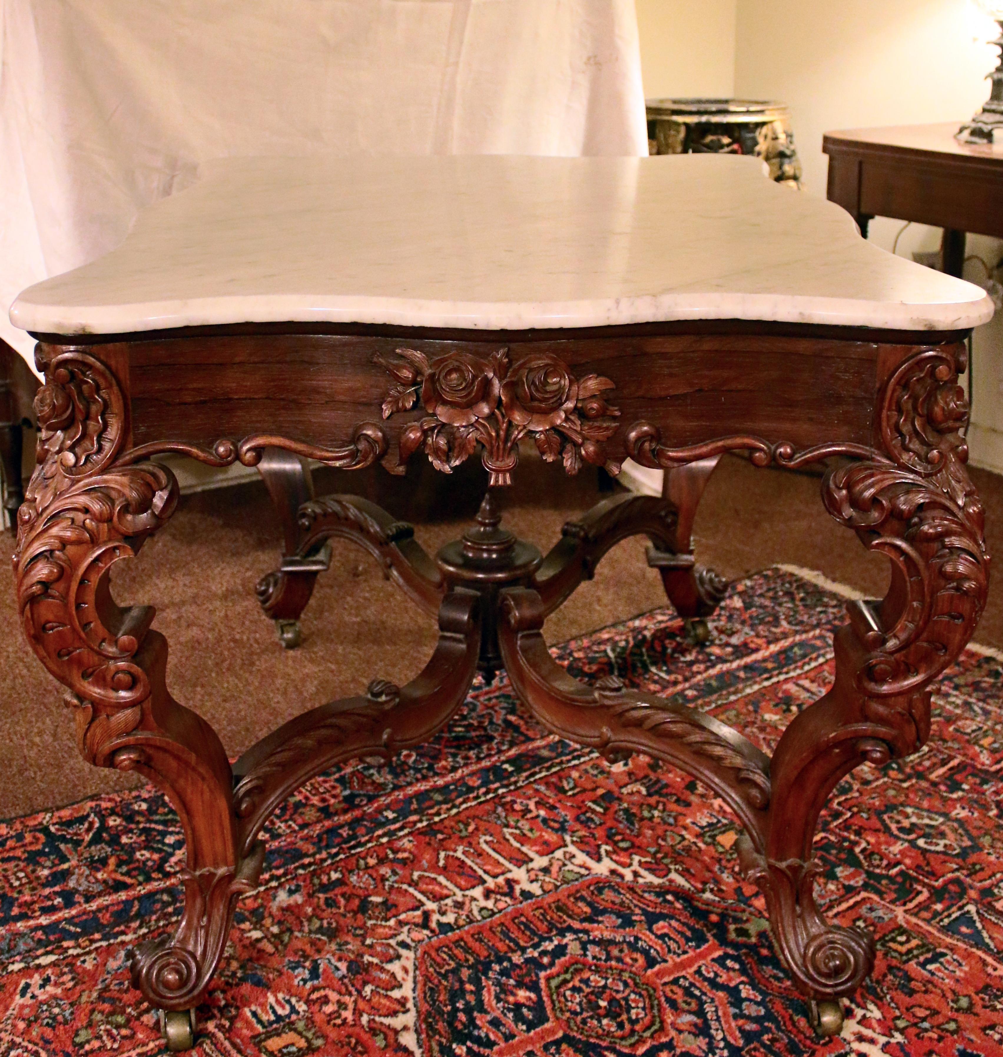 Rococo Revival center table attributed to the prestigious New York firm of Joseph Meeks. Heavily hand carved rosewood featuring floral bouquets and rosettes, graceful serpentine legs, fanciful stretchers and beveled white marble top. See