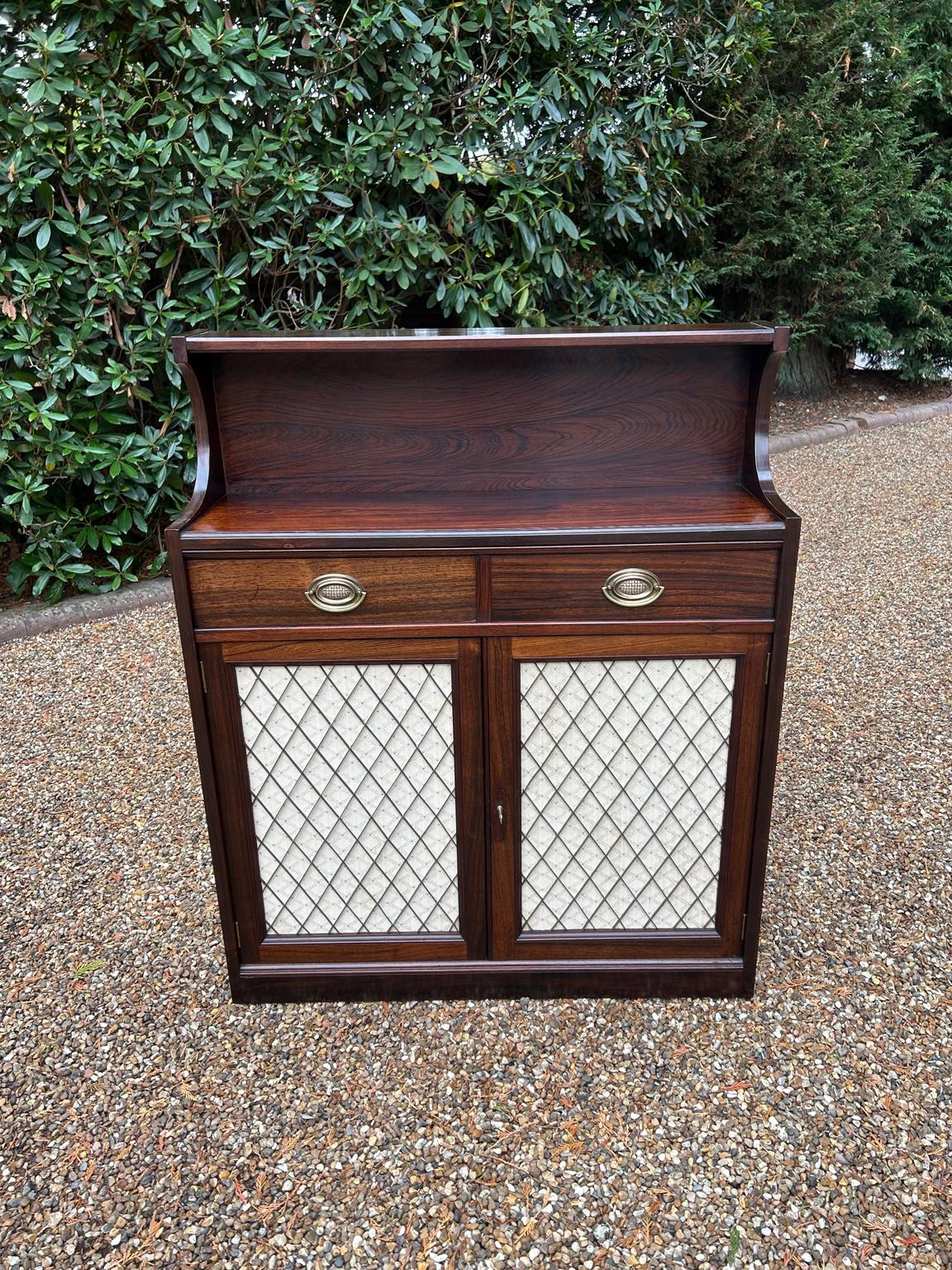 Chiffoniera in palissandro del XIX secolo di alta qualità, con un ripiano posteriore sopra due cassetti rivestiti in mogano con maniglie ovali in ottone. Un paio di porte con griglia in ottone si aprono su un ripiano regolabile in palissandro