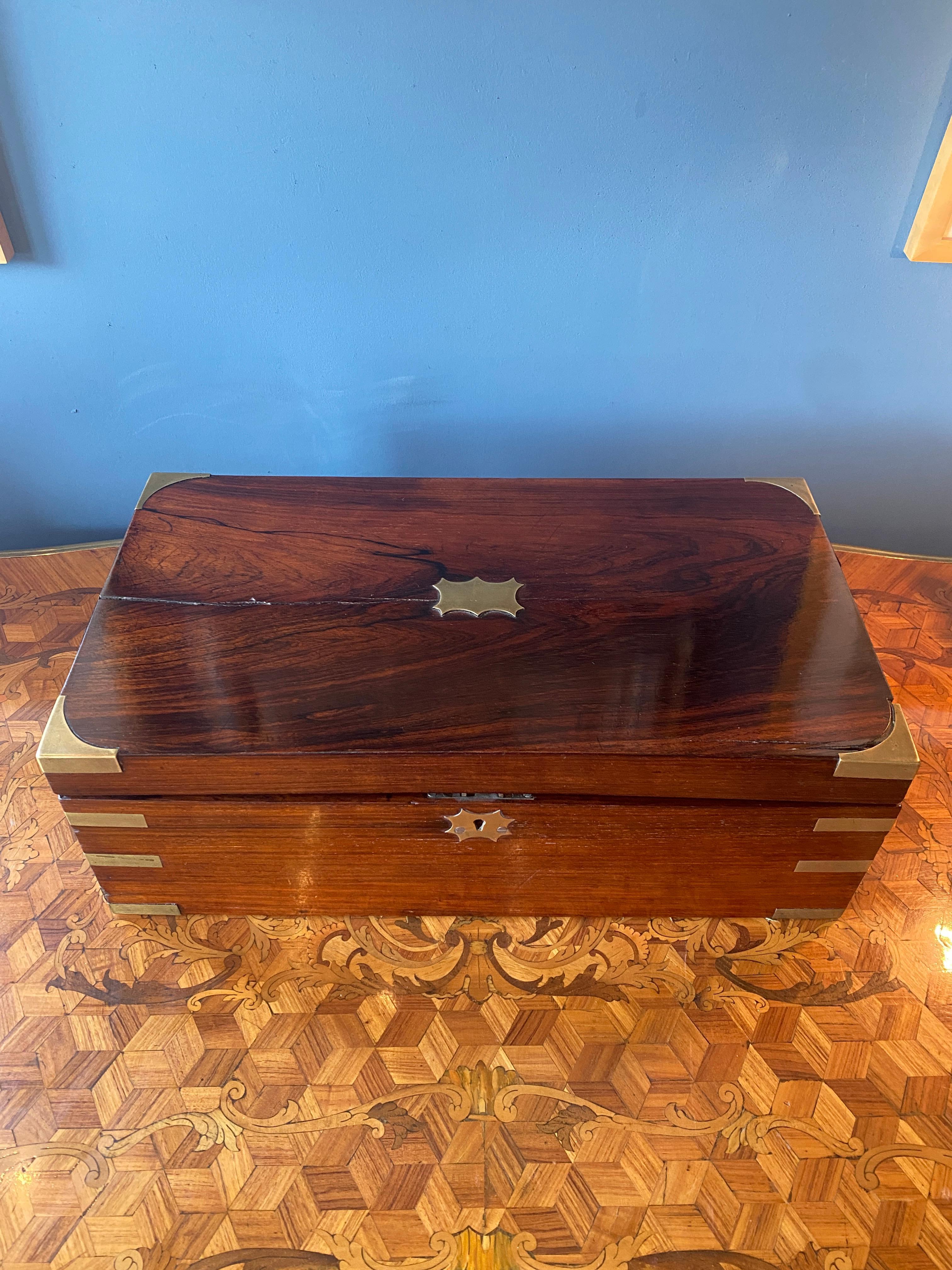 19th century rosewood English Campaign lap desk. Gorgeous highly polished rosewood and brass. Two hidden drawers fitted inside. Flip lid to open for two storage compartments. One side drawer with a locking brass pin. The writing surface is olive