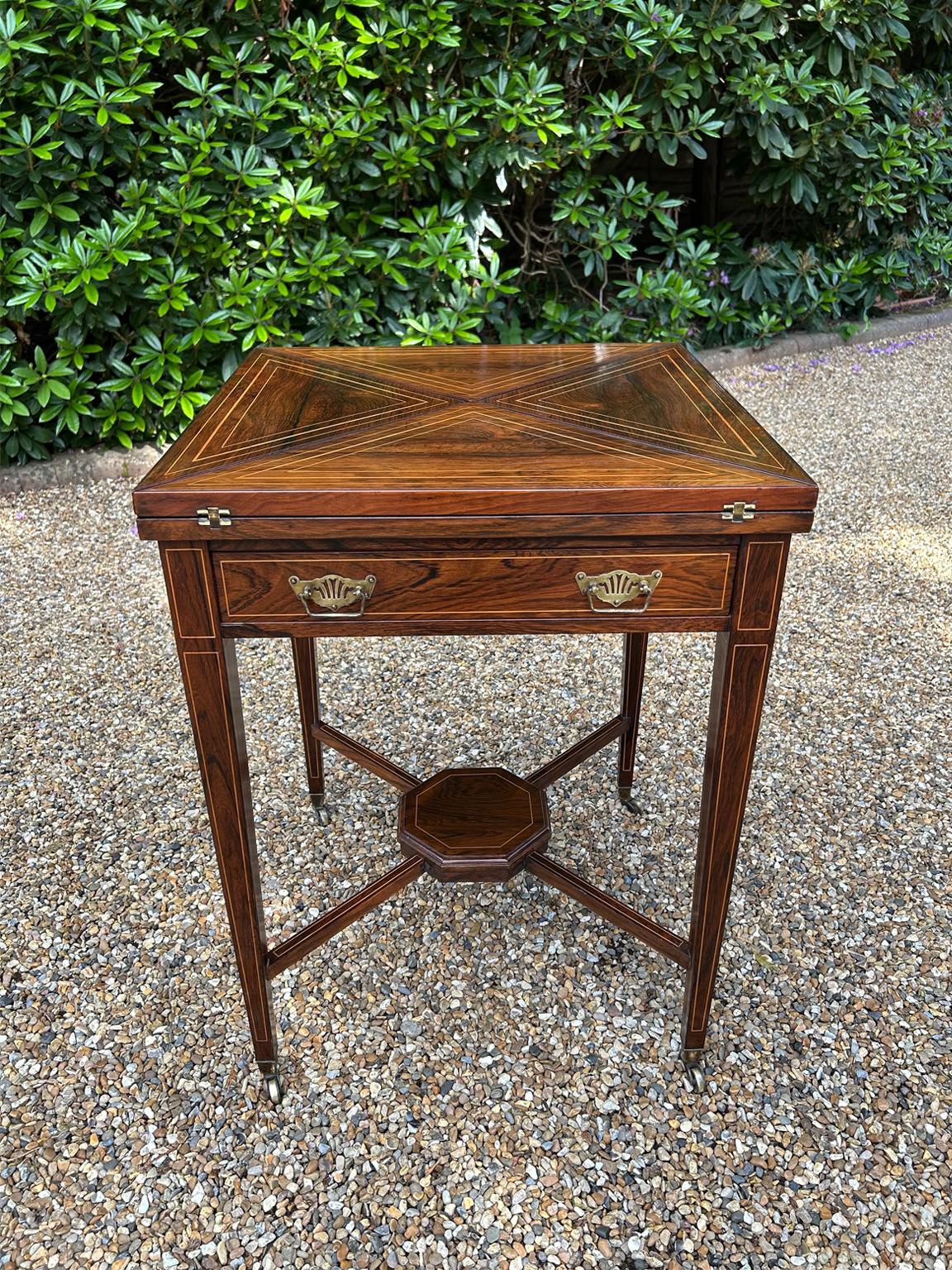 19th Century Edwardian Rosewood Envelope Card Table with line lay throughout. With a fitted mahogany lined drawer, brass handles raised upon square tapering legs with undertier and castors. Rotates 90 degrees, to open up into a card table with