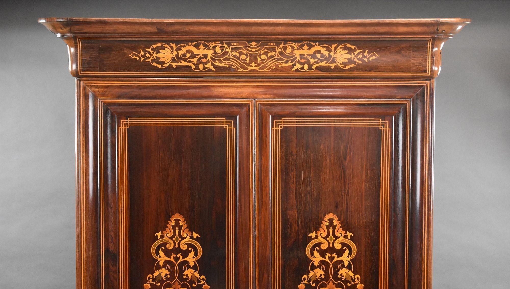 19th Century continental rosewood inlaid wardrobe with profusely inlaid cornice top with double doors each with decorative inlay, when opened reveals a single hanging rail below this has one inlaid drawer with key and a secret drawer below, stands