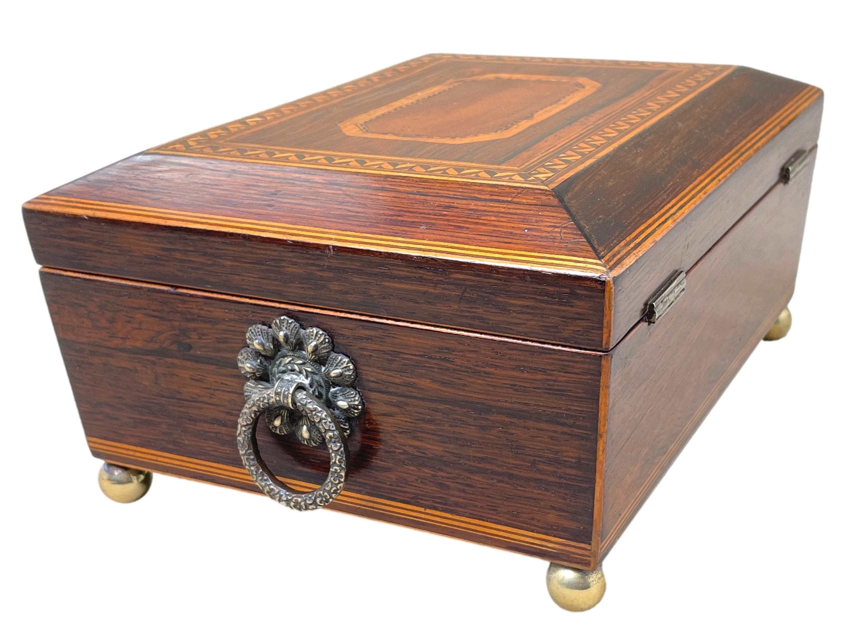 A charming mid 19th century rosewood jewellery box having attractive inlaid decoration to hinged lid enclosing lined interior with elegant original brass ring handles raised on original brass ball feet.

A sweet little jewellery box of sensible,
