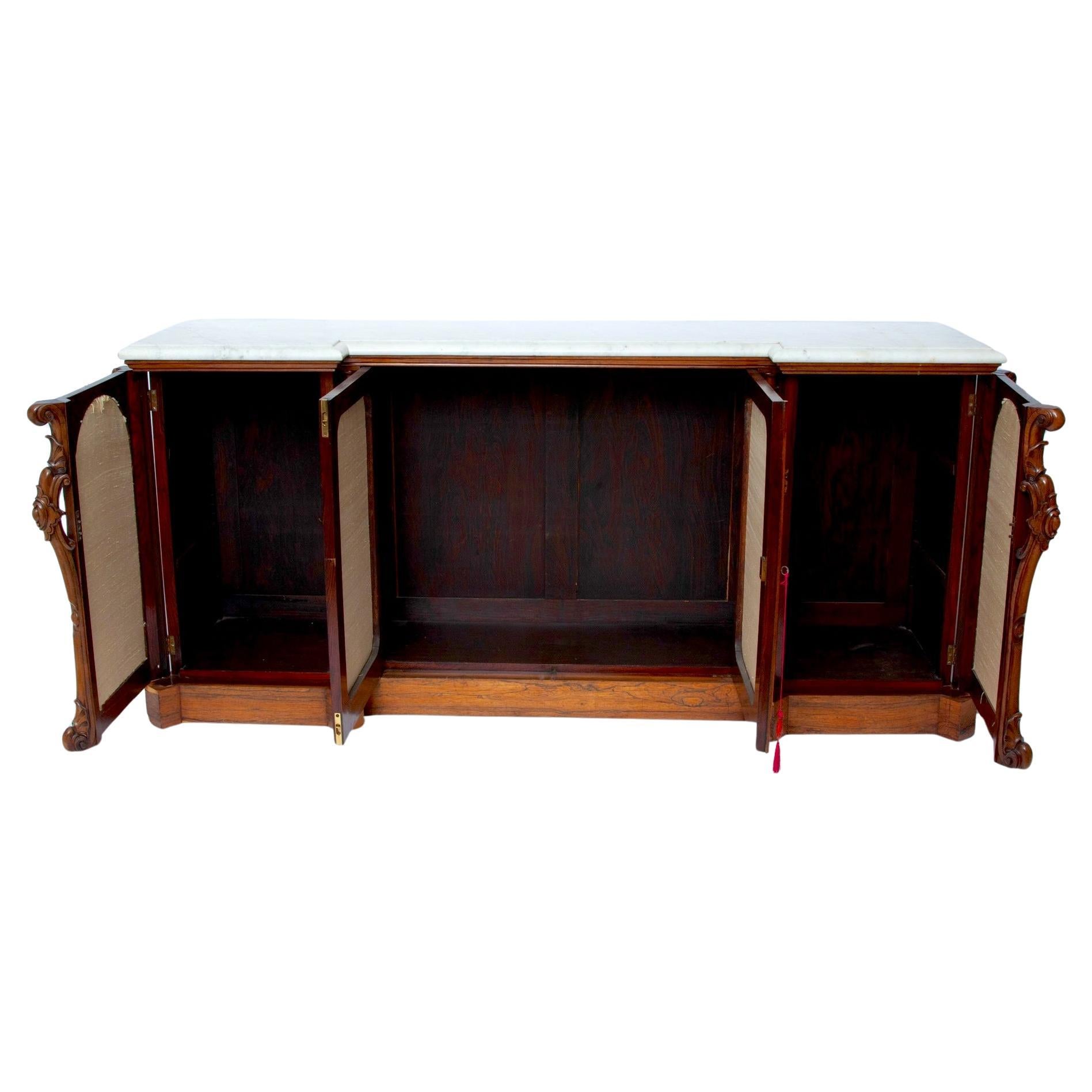 Questa credenza vittoriana in palissandro, realizzata nel 1865 circa, rappresenta un'aggiunta impressionante a qualsiasi spazio grazie alle sue caratteristiche distintive e al suo design senza tempo. Poggiato su una robusta base a plinto, il mobile