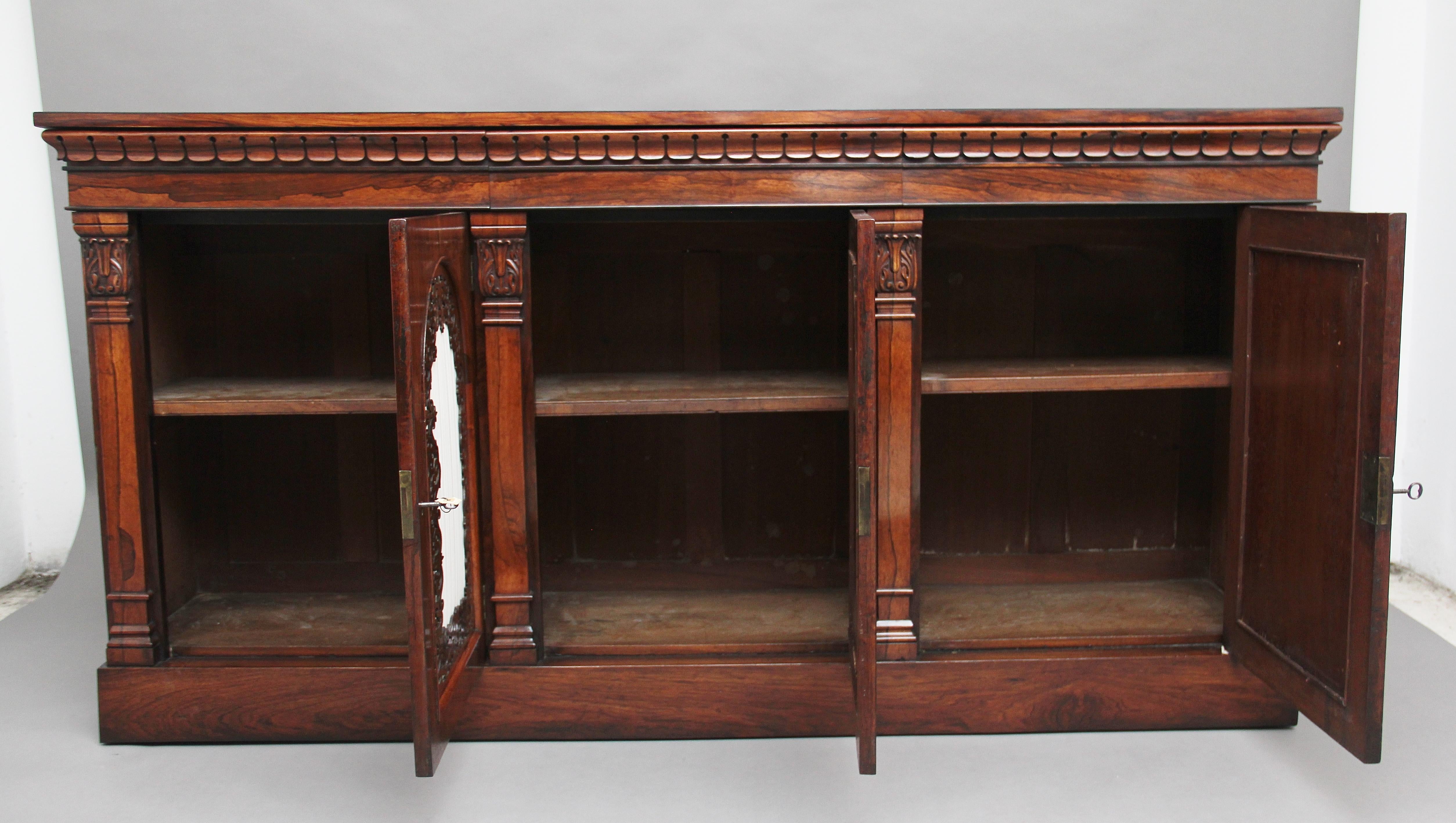 Early 19th century rosewood side cabinet, the wonderfully figured rectangular crossbanded top above a frieze with carved decoration, including three frieze drawers which are mahogany lined, below having three arch-panelled doors with fret-pierced