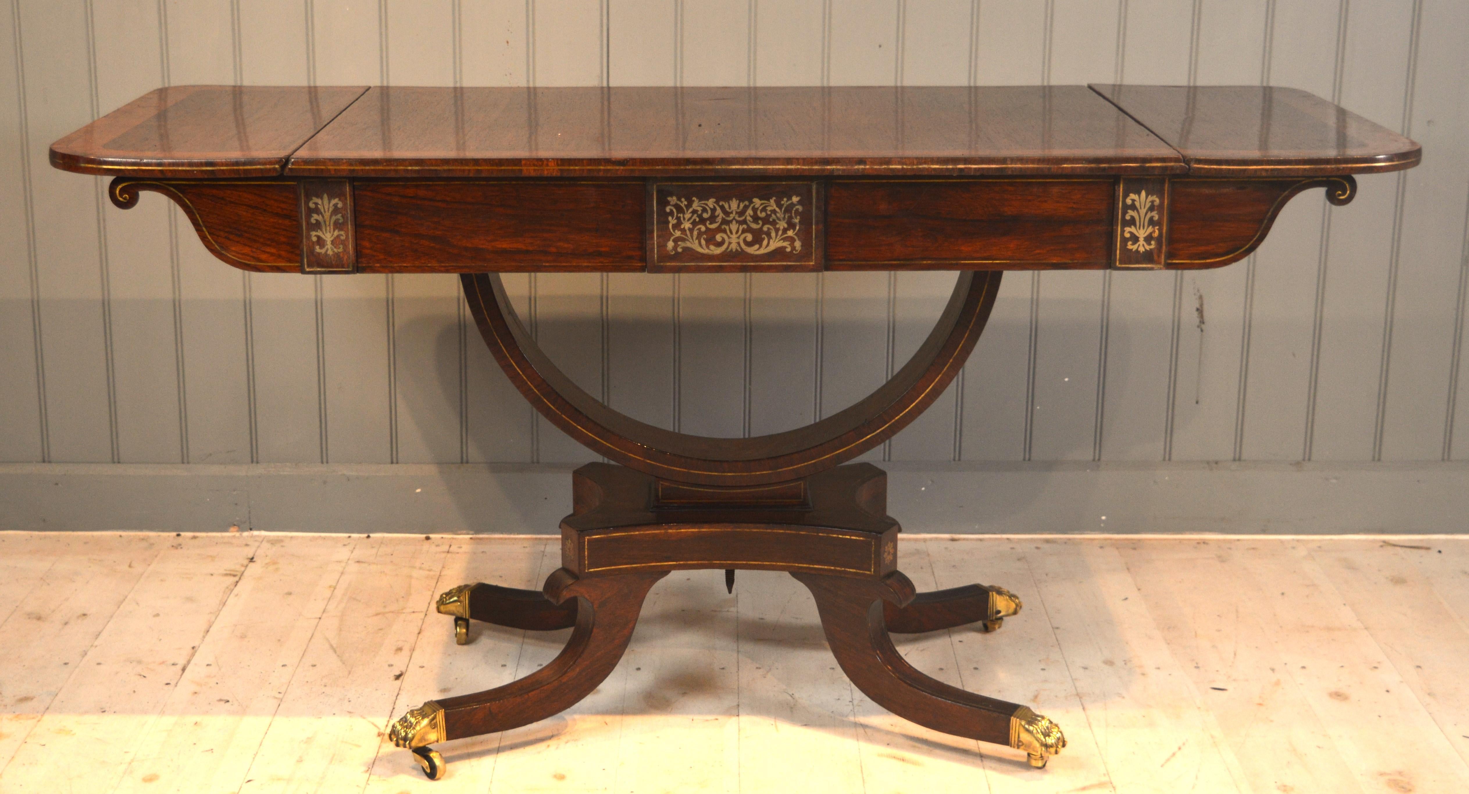 Here we have a very good quality rosewood and brass inlayed sofa table with amboyna banding in the top surface .
It also has superb brass cast feet and casters the brass inlay is top class ,tables with this type of finish were for wealthy homes in