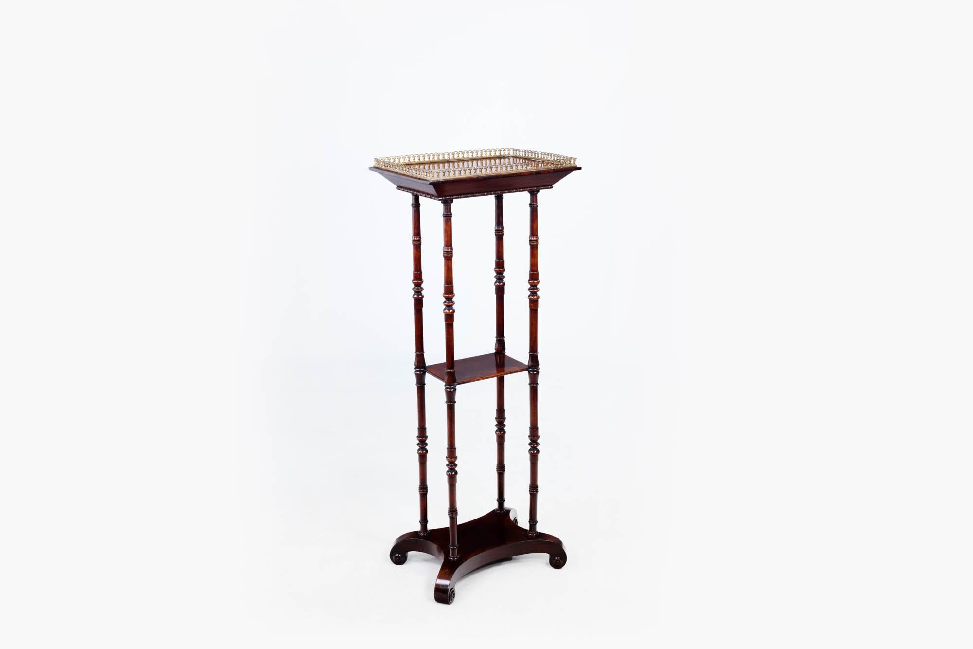 19th century Rosewood three-tier what-not. The top shelf is surmounted with a brass gallery rail and carved cockbead detail to the edges. The whole piece stands supported by four finely carved bolstered pillars. The piece terminates on scrolled feet.