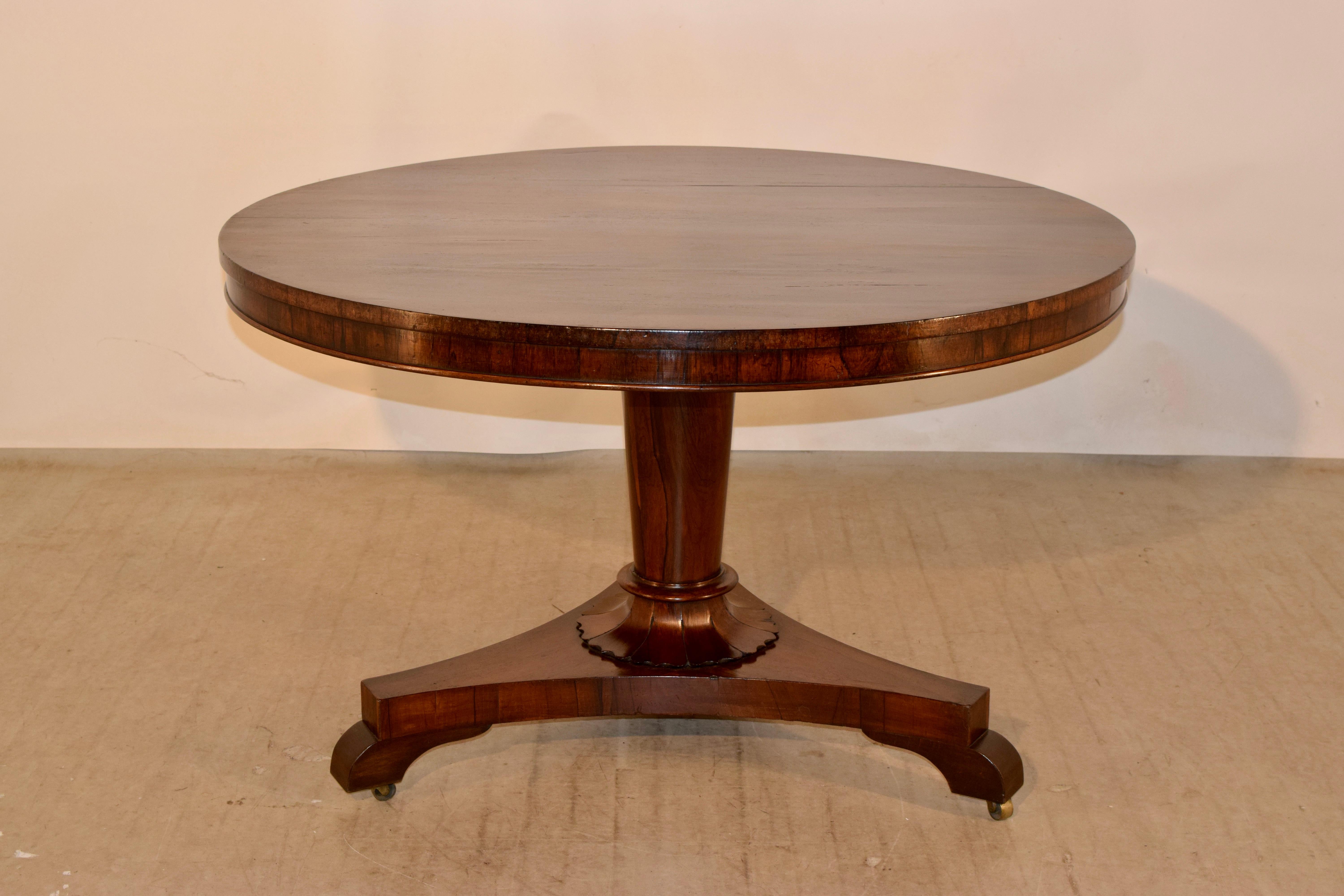 19th century fine quality tilt-top centre table, having a tilt-top with outstanding rosewood grain raised on a simple column with a floral shaped base, terminating in a tricorn base with shaped feet and castors. Measurements when tilt-top is down