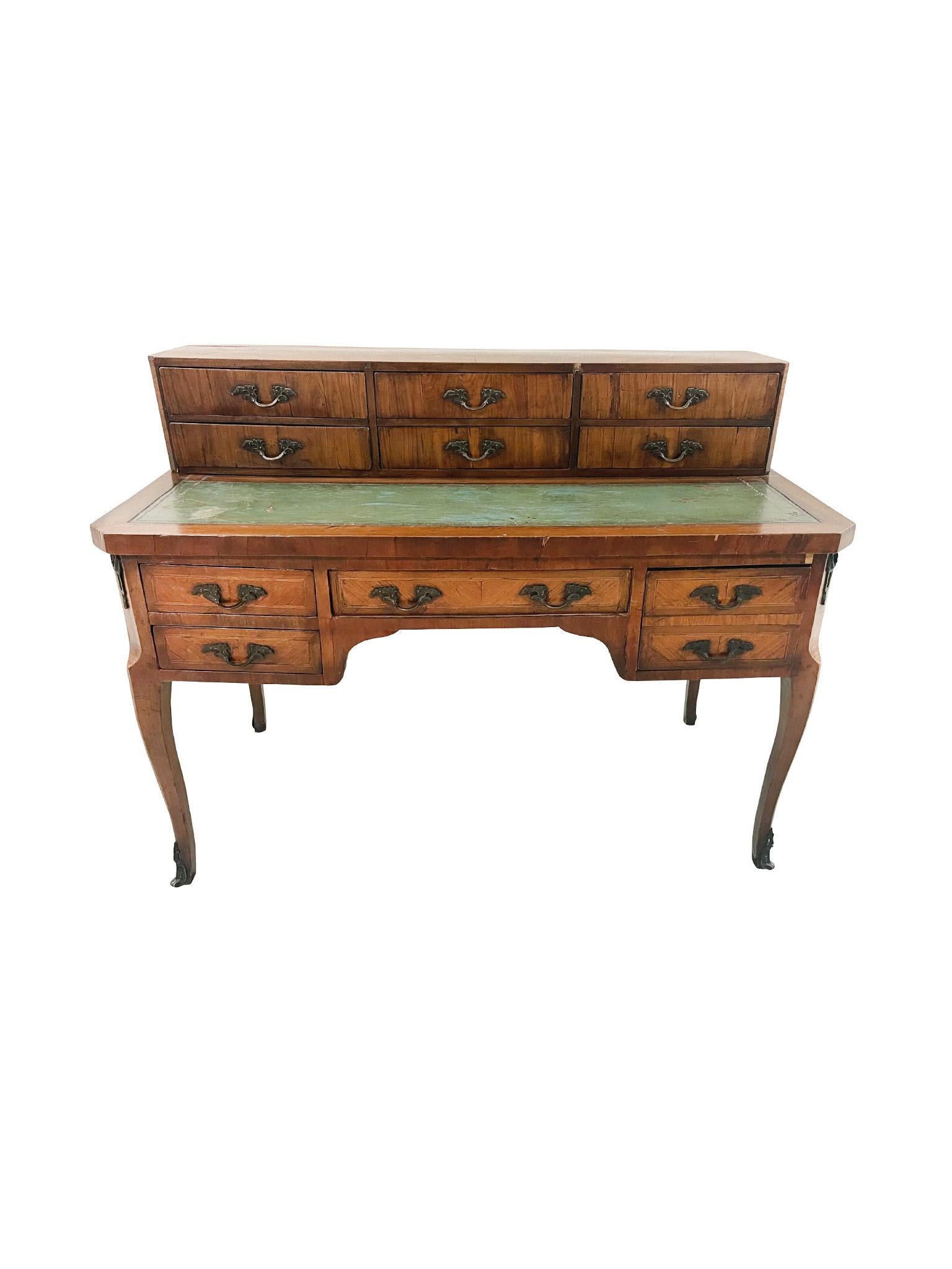 Hand-crafted in the 19th Century, this Louis XV-style desk is comprised of rosewood with decorative veneer, green leather top, and bronze mounts and pulls. The flat-top cabinet consists of 6 small drawers. The desk is equipped with a central drawer