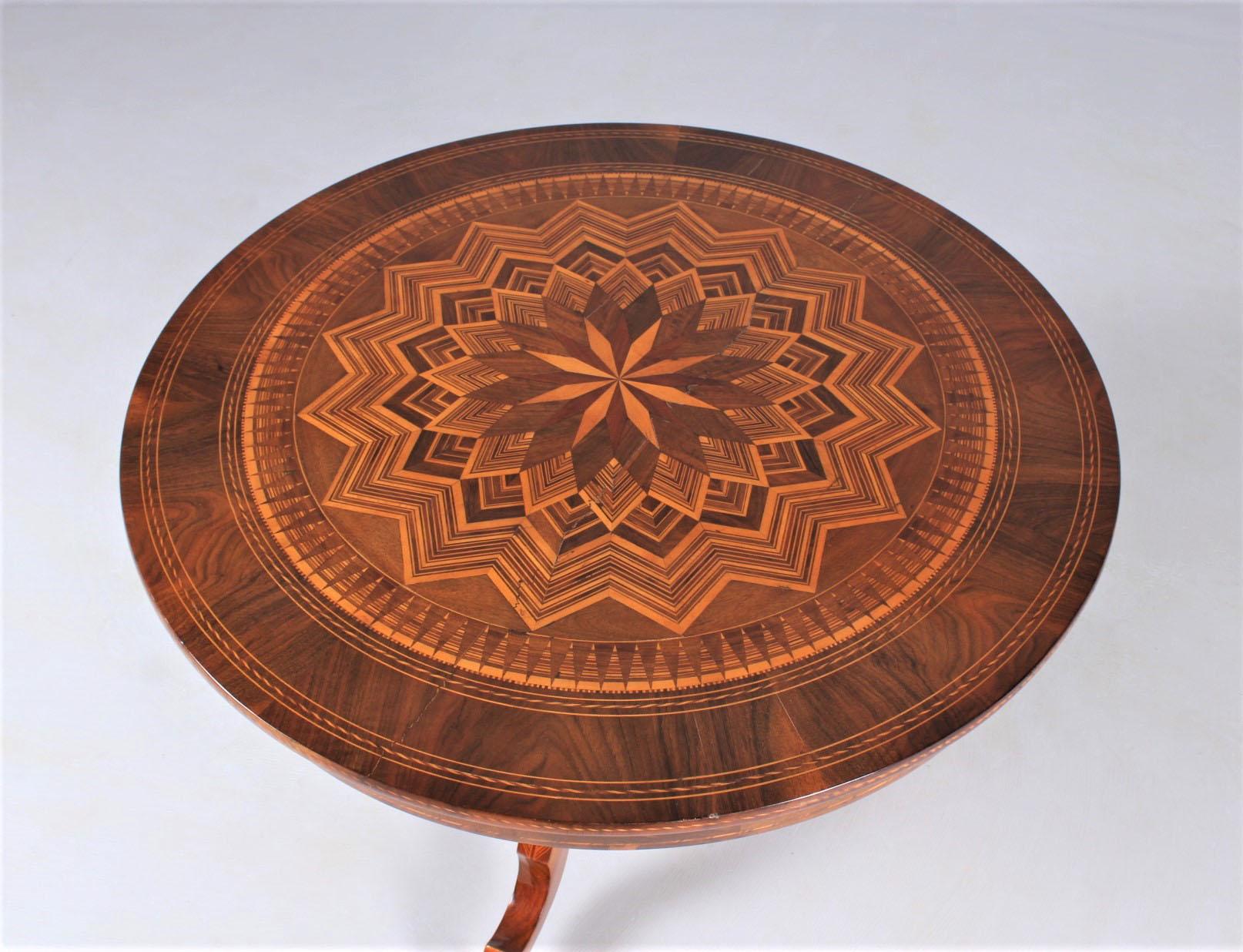 Round side table, coffee table with geometric inlays. 
The main surfaces are veneered in walnut, the marquetry is made of various woods such as mahogany and maple among others.

Measures: Height 64 cm, diameter 90 cm.

The assembling of